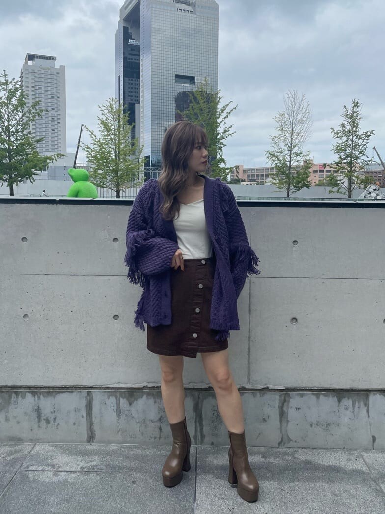 ブラウン系のスカート、ベージュ系のブーツ、パープル系のカーディガン/ボレロを着用したレディースの秋コーディネートの4枚目の写真