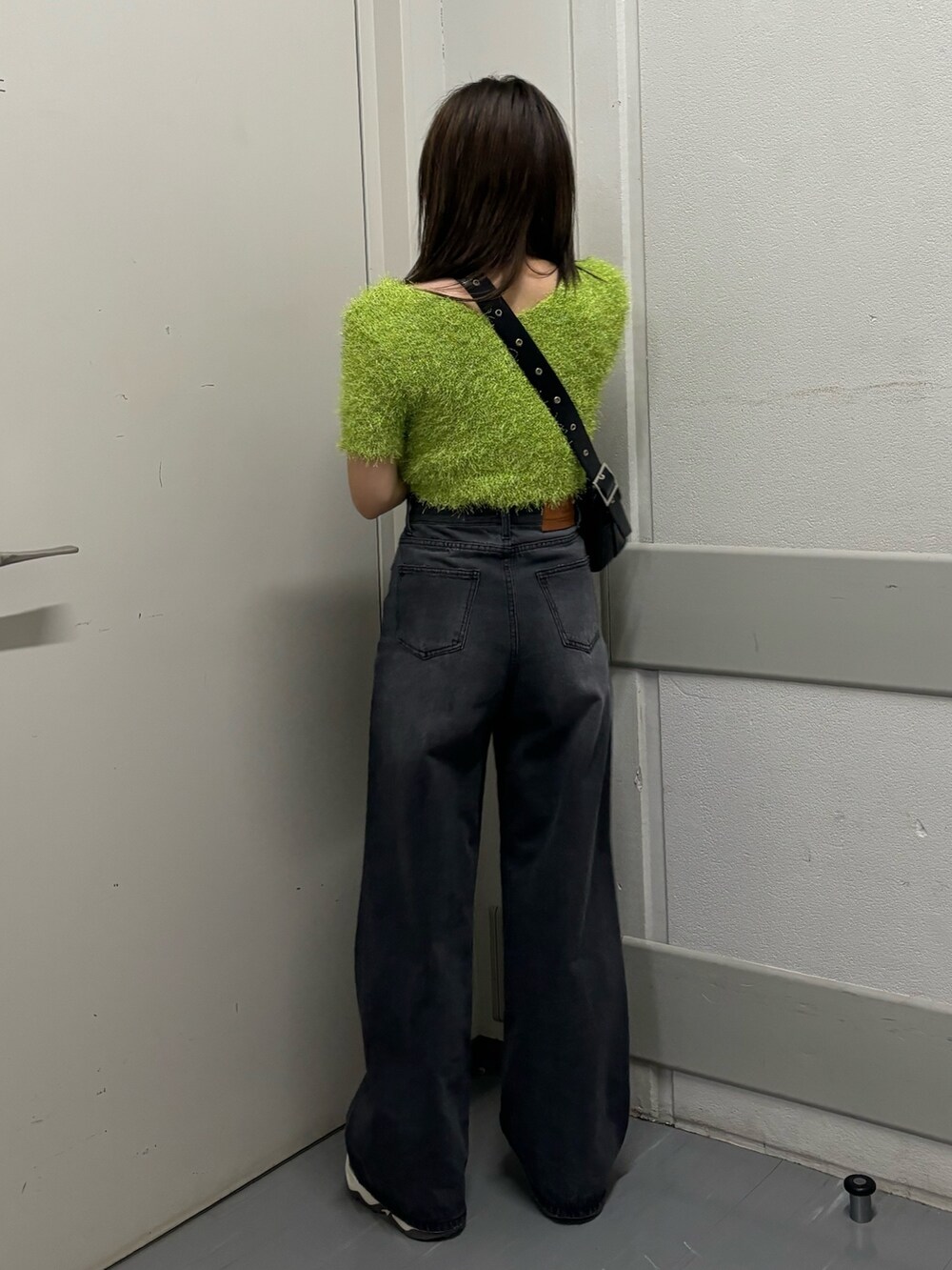 ブラック系のショルダーバッグ、グリーン系のニット/セーター、ブラック系のデニムパンツを着用したレディースの春コーディネートの4枚目の写真