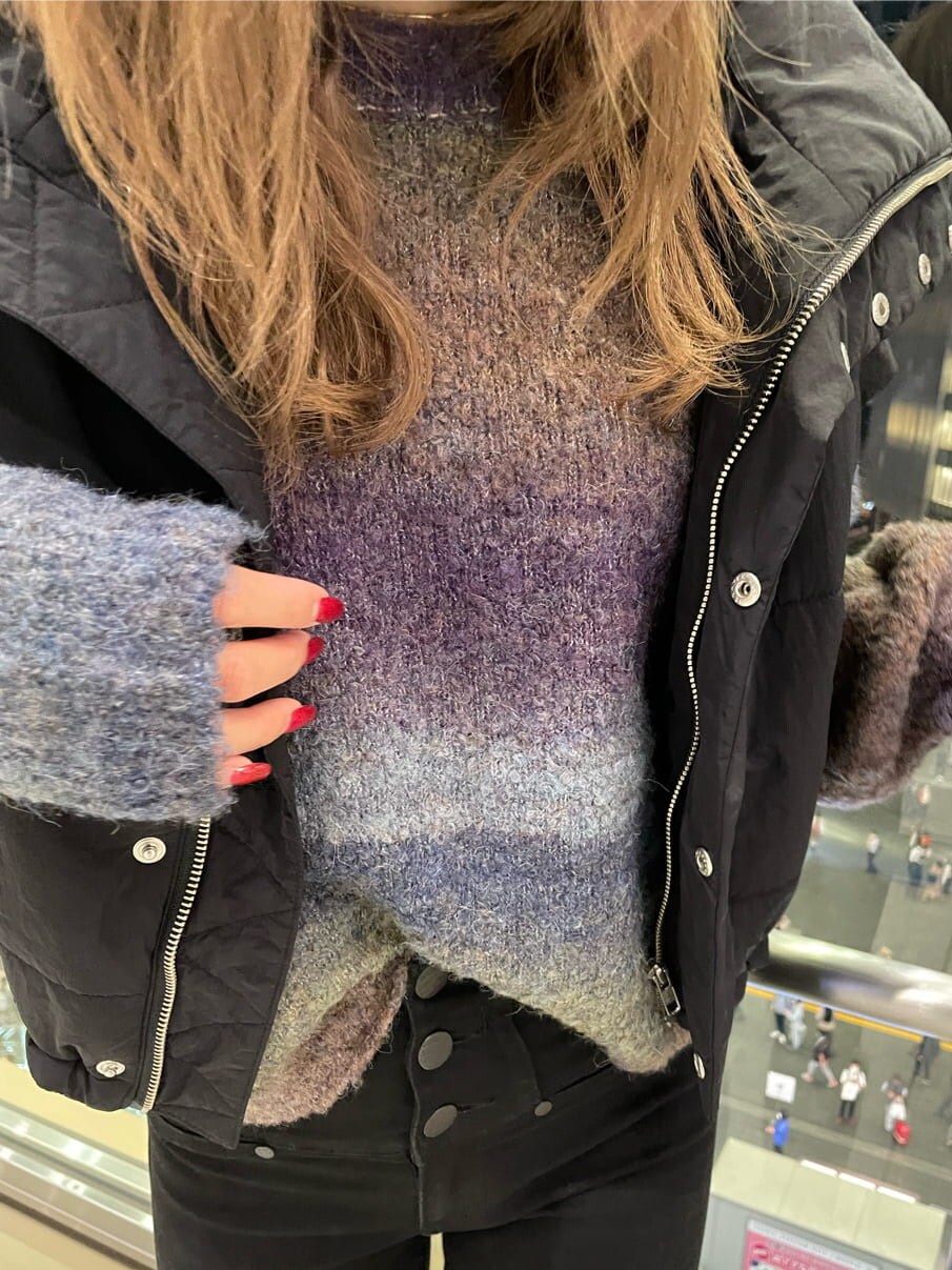 ブラック系のダウンベスト、ブラック系のブーツ、パープル系のニット/セーターを着用したレディースの秋コーディネートの4枚目の写真