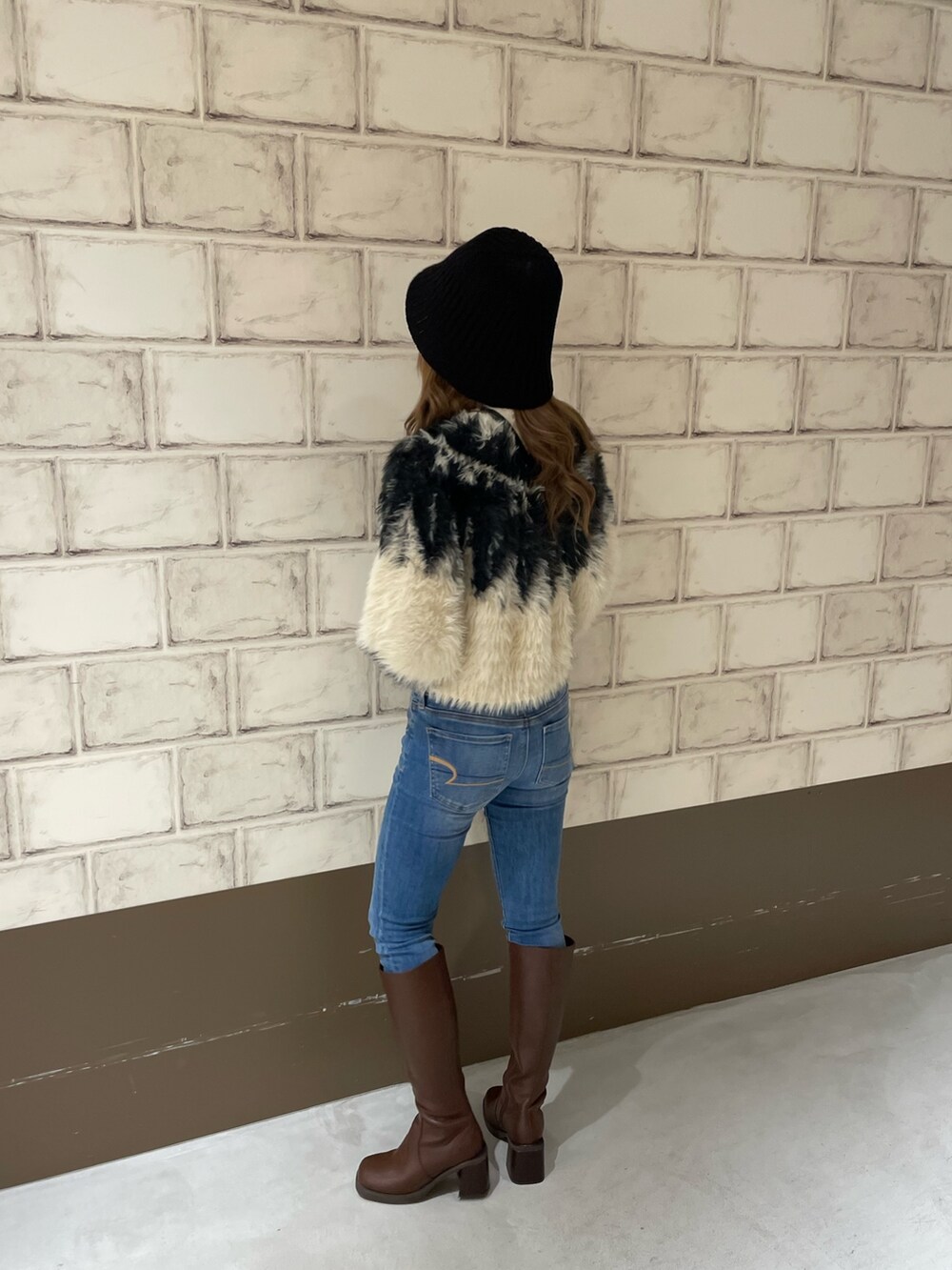 ホワイト系のニット/セーター、ブラウン系のブーツ、ブラック系のハットを着用したレディースの秋コーディネートの3枚目の写真