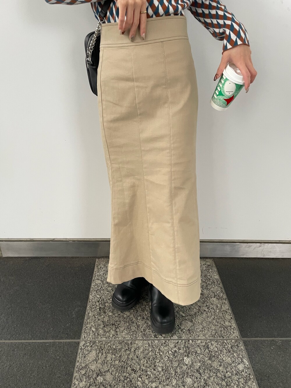 ブラック系のショルダーバッグ、オレンジ系のニット/セーター、ベージュ系のスカートを着用したレディースの秋コーディネートの8枚目の写真