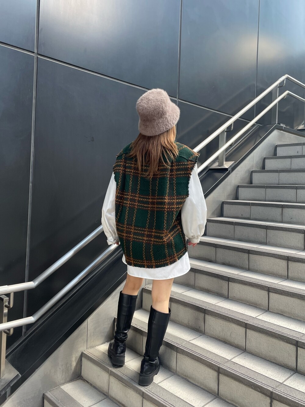 グリーン系のワンピース、ブラック系のブーツ、ベージュ系のハットを着用したレディースの冬コーディネートの3枚目の写真