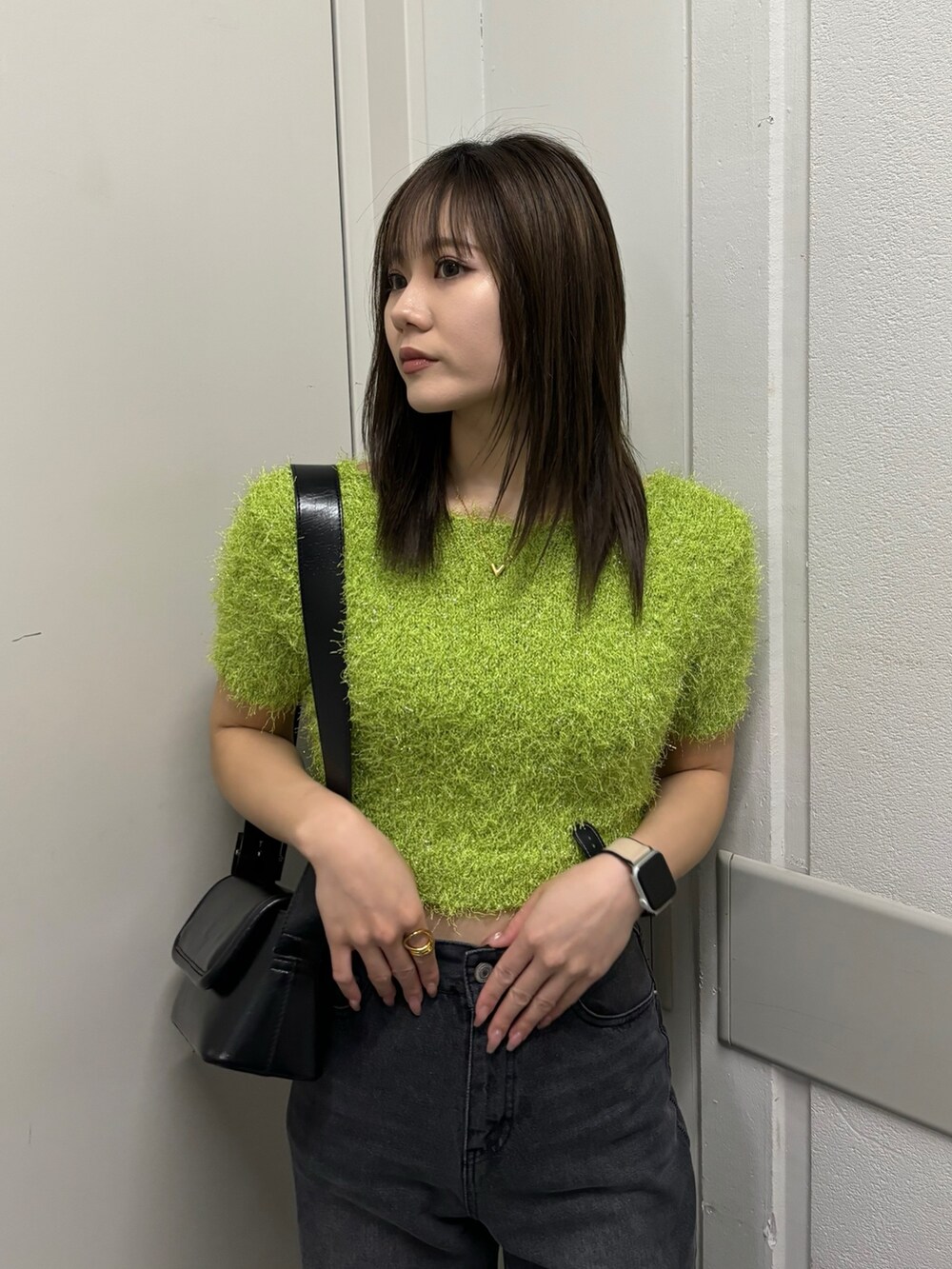 ブラック系のショルダーバッグ、グリーン系のニット/セーター、ブラック系のデニムパンツを着用したレディースの春コーディネートの5枚目の写真