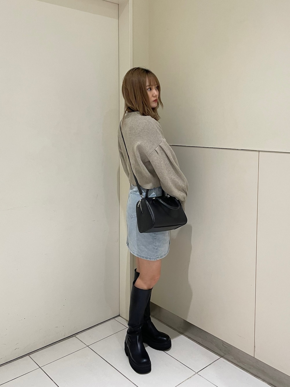 ホワイト系のカーディガン/ボレロ、ブラック系のブーツ、ブラック系のハンドバッグを着用したレディースの春コーディネートの3枚目の写真