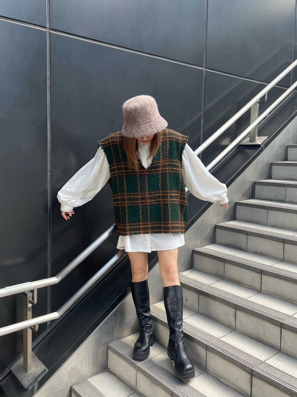 グリーン系のワンピース、ブラック系のブーツ、ベージュ系のハットを着用したレディースの冬コーディネートの2枚目の写真