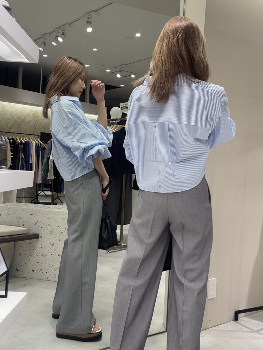 ブルー系のシャツ/ブラウス、グレー系のスラックス、その他のサンダルを着用したレディースの春コーディネートの2枚目の写真