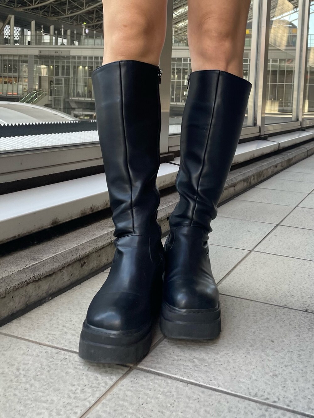 オレンジ系のパーカー、ブラック系のブーツを着用したレディースの秋コーディネートの7枚目の写真