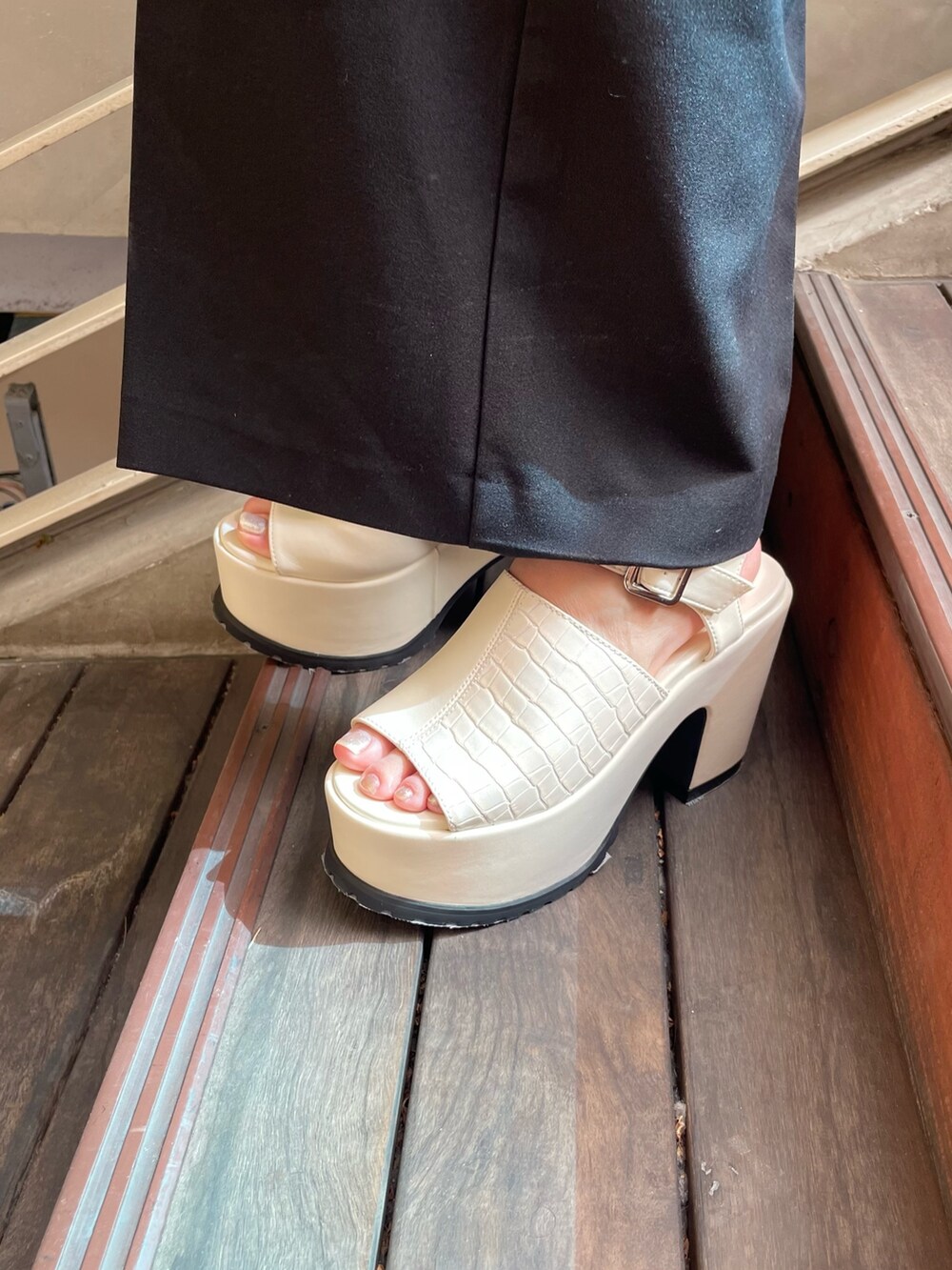 ブラック系のTシャツ/カットソー、ブラック系のスラックス、ホワイト系のサンダルを着用したレディースの春コーディネートの8枚目の写真