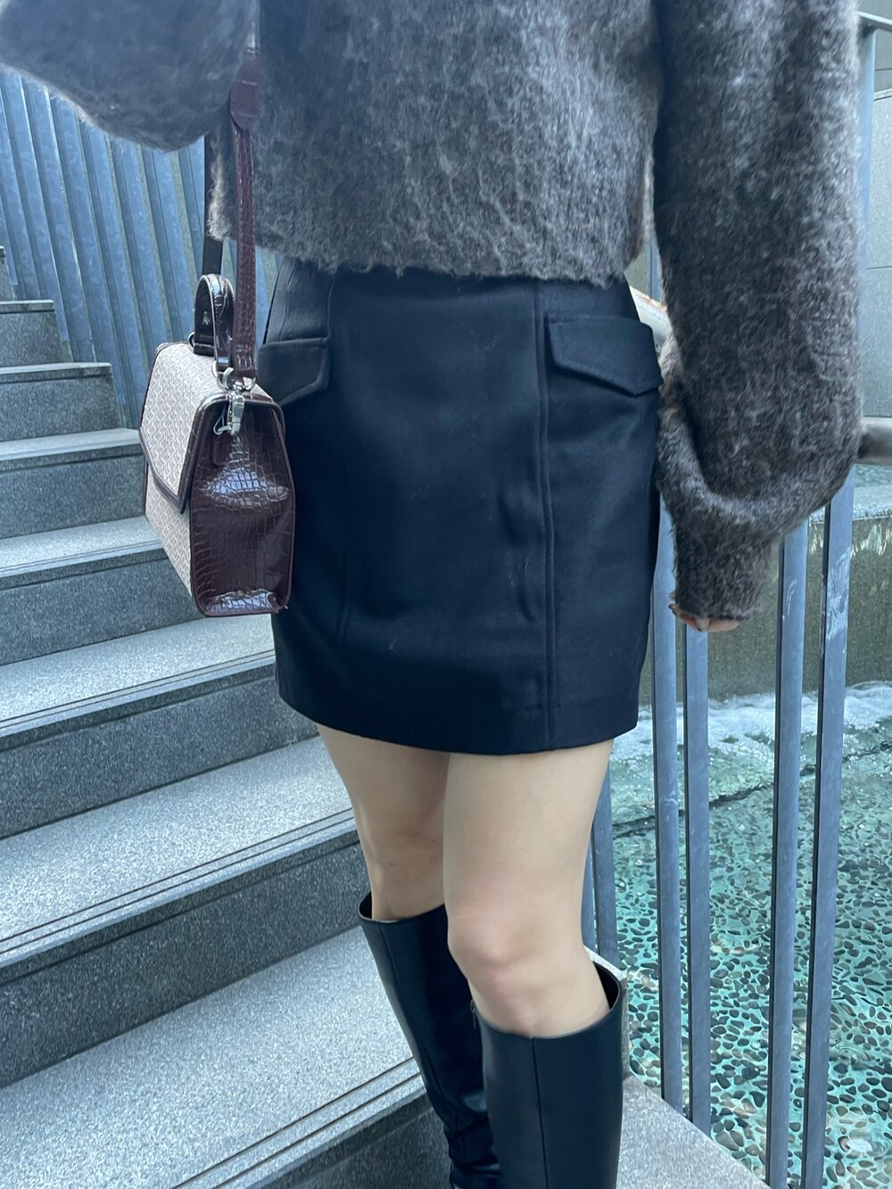 ブラウン系のニット/セーター、ブラック系のスカート、その他のハンドバッグを着用したレディースの秋コーディネートの7枚目の写真