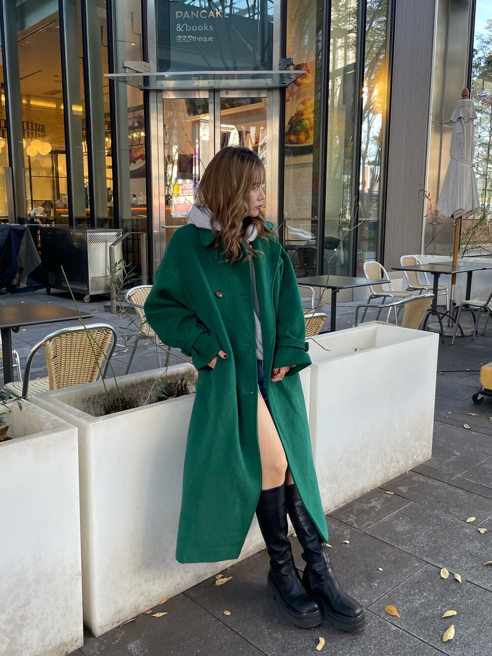 グリーン系のチェスターコート、ブラック系のブーツを着用したレディースの秋コーディネートの3枚目の写真