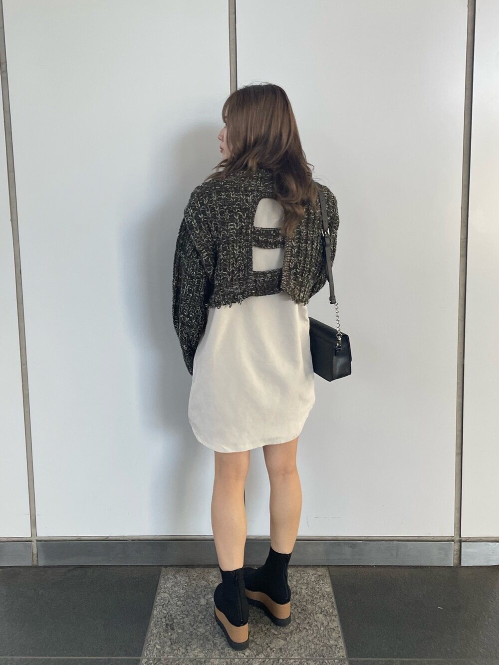 グリーン系のワンピース、ブラック系のショルダーバッグ、ブラック系のブーツを着用したレディースの秋コーディネートの3枚目の写真