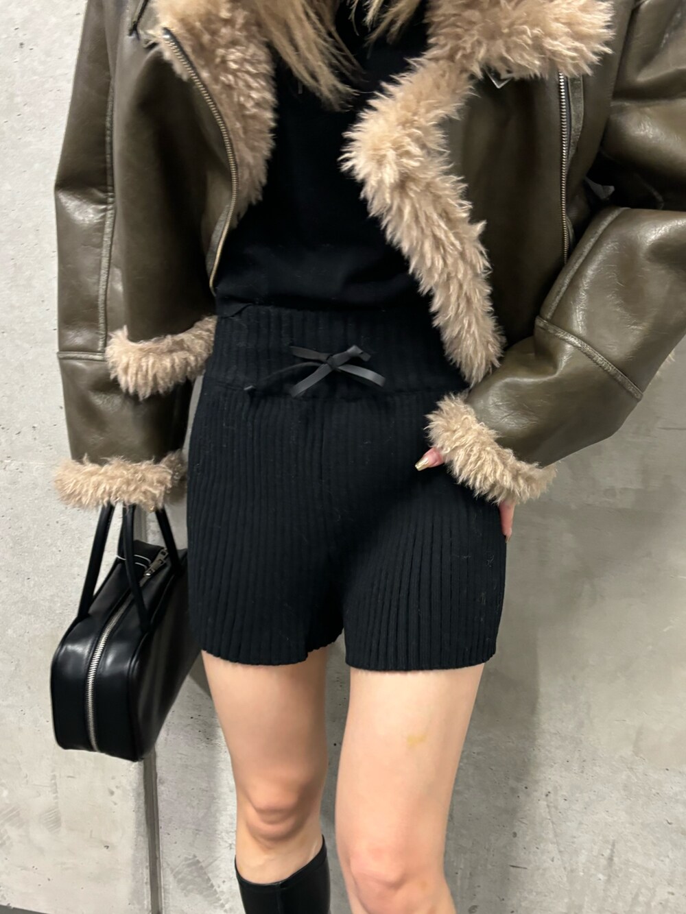 ブラック系のその他パンツ、ブラック系のブーツ、グリーン系のムートンコートを着用したレディースの夏コーディネートの8枚目の写真