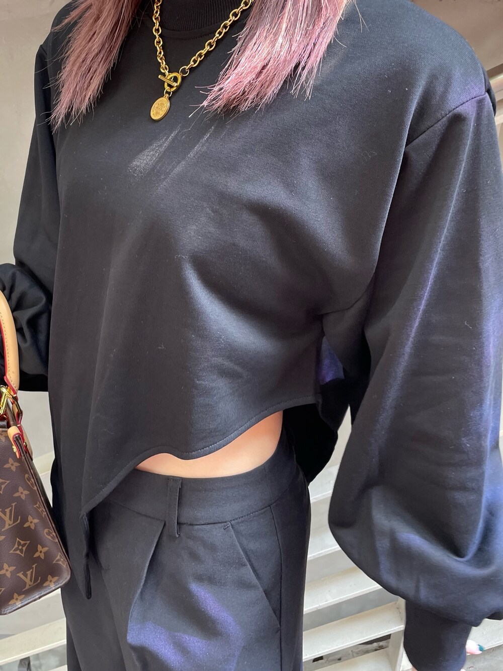 ブラック系のTシャツ/カットソー、ブラック系のスラックス、ホワイト系のサンダルを着用したレディースの春コーディネートの6枚目の写真