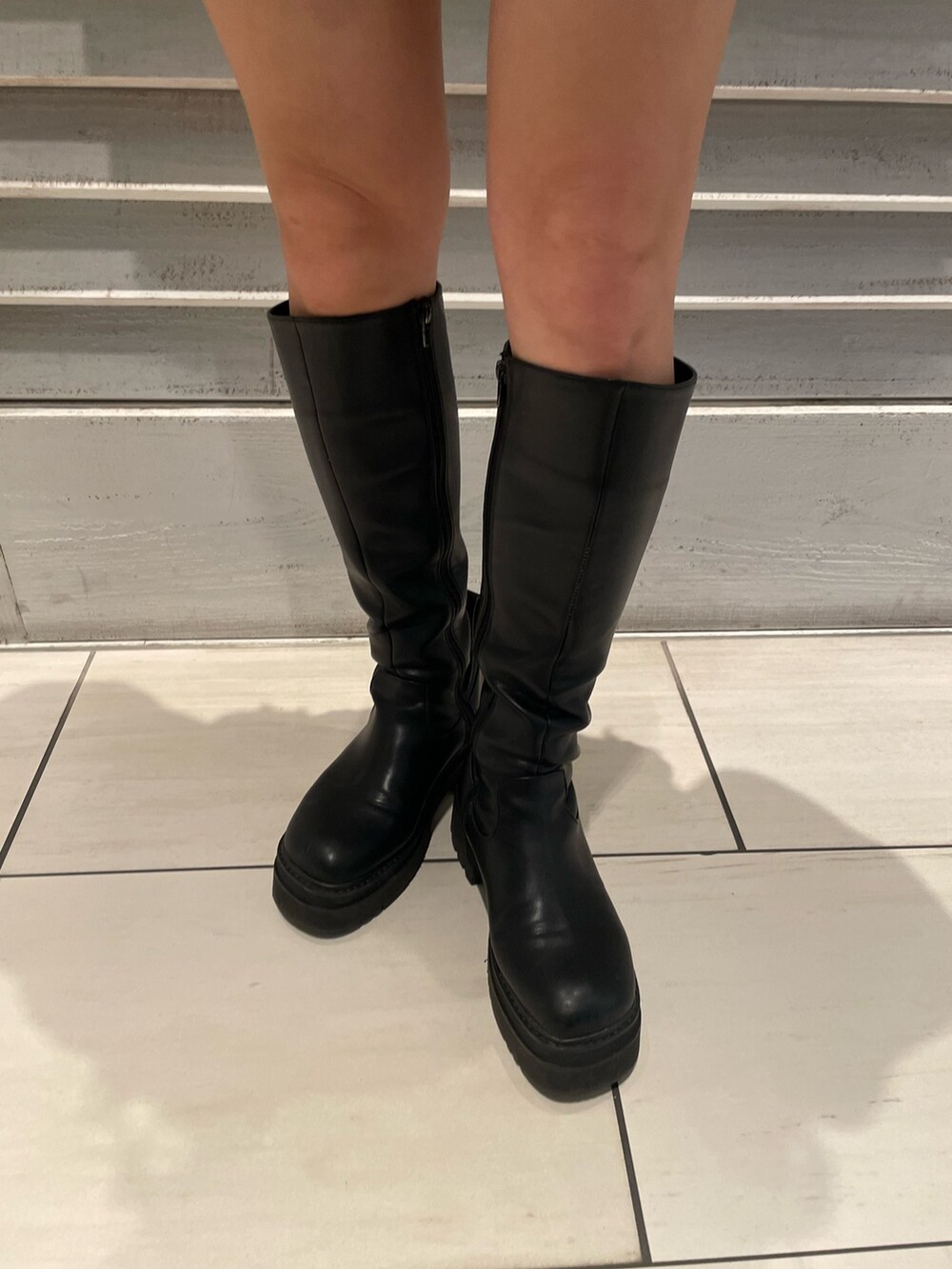 ホワイト系のニット/セーター、ブラック系のブーツ、その他のショルダーバッグを着用したレディースの秋コーディネートの7枚目の写真