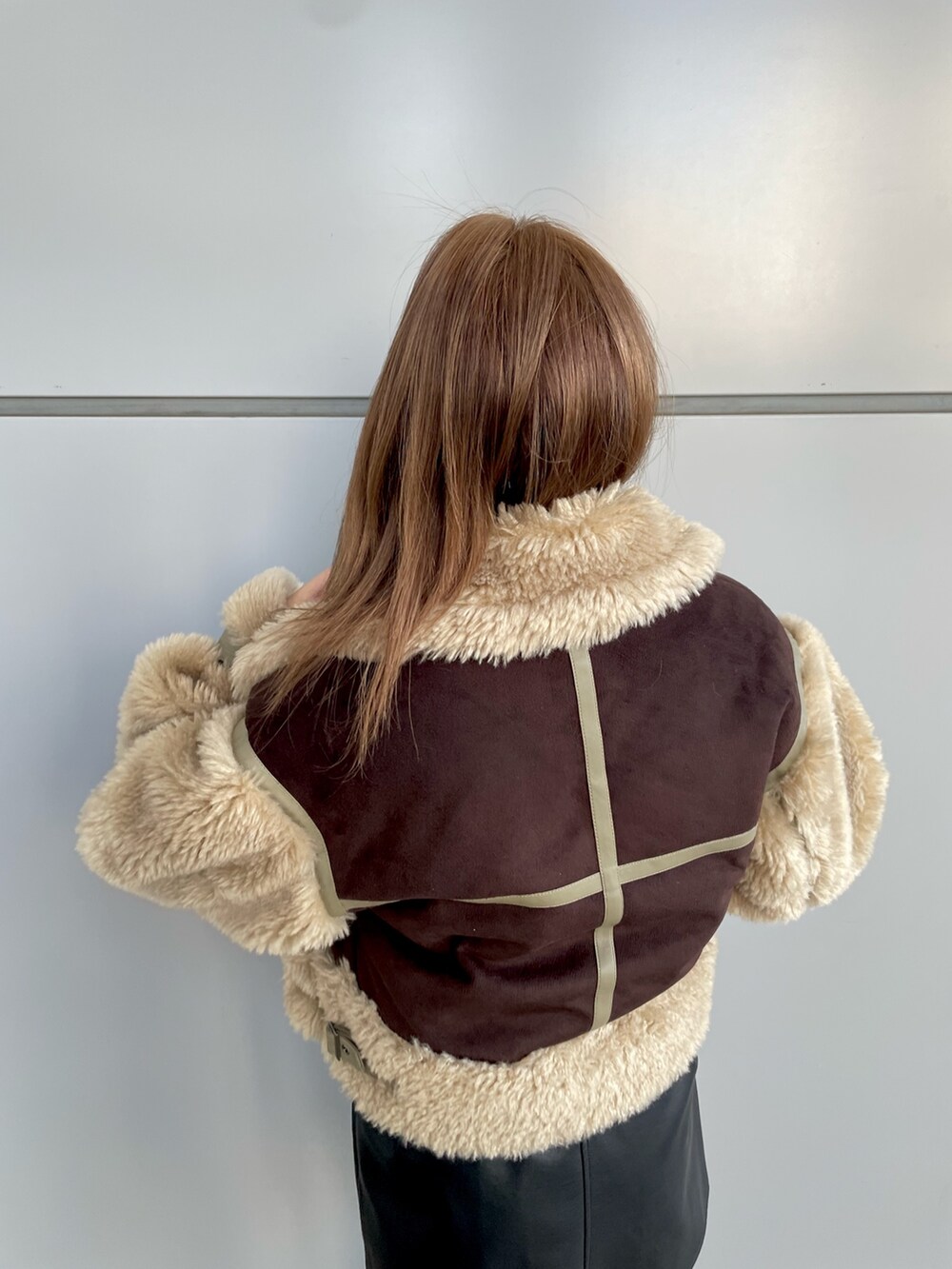 ブラック系のワンピース、ホワイト系のニット/セーター、ブラウン系のムートンコートを着用したレディースの冬コーディネートの6枚目の写真