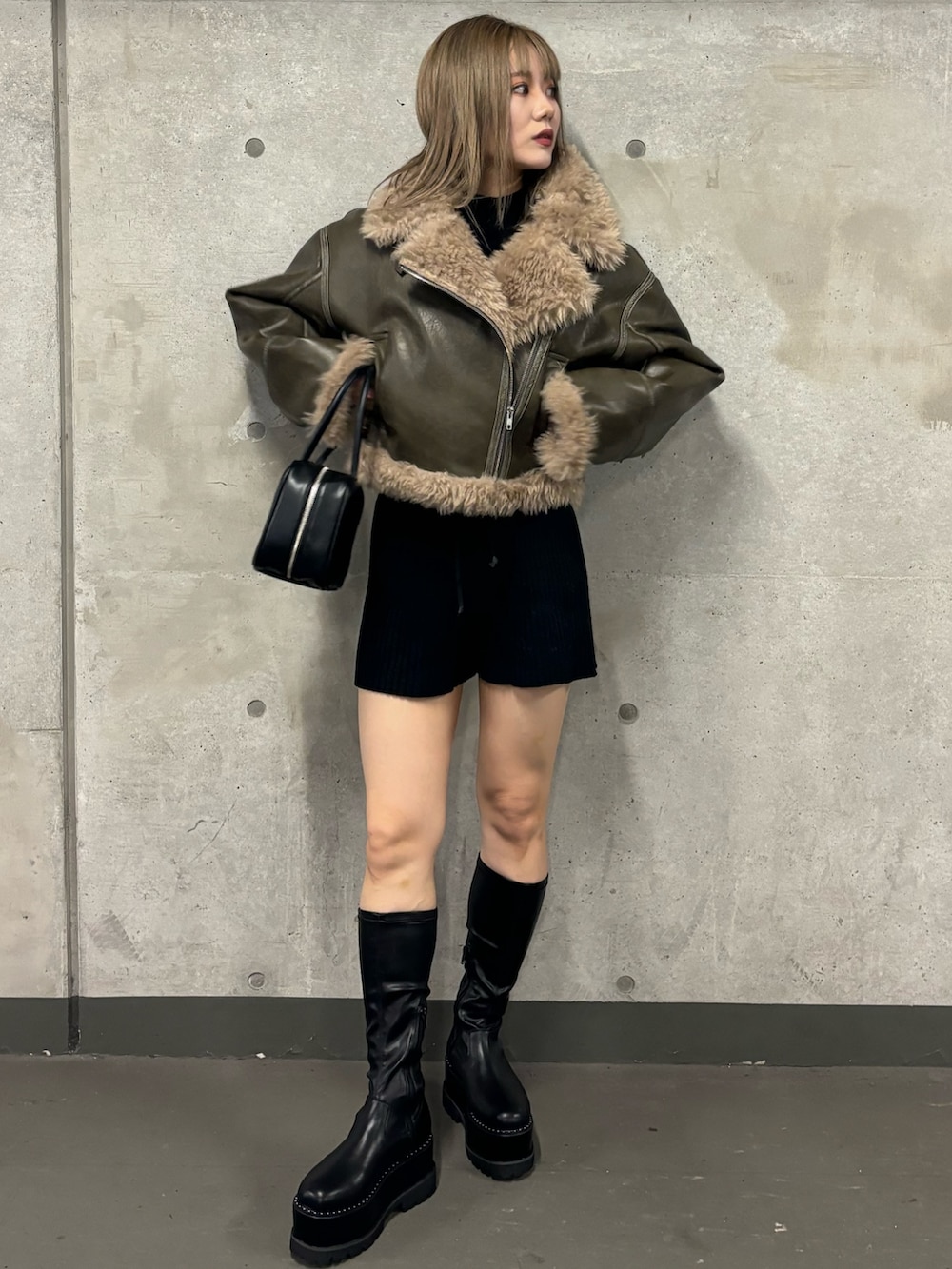 ブラック系のその他パンツ、ブラック系のブーツ、グリーン系のムートンコートを着用したレディースの夏コーディネートの2枚目の写真