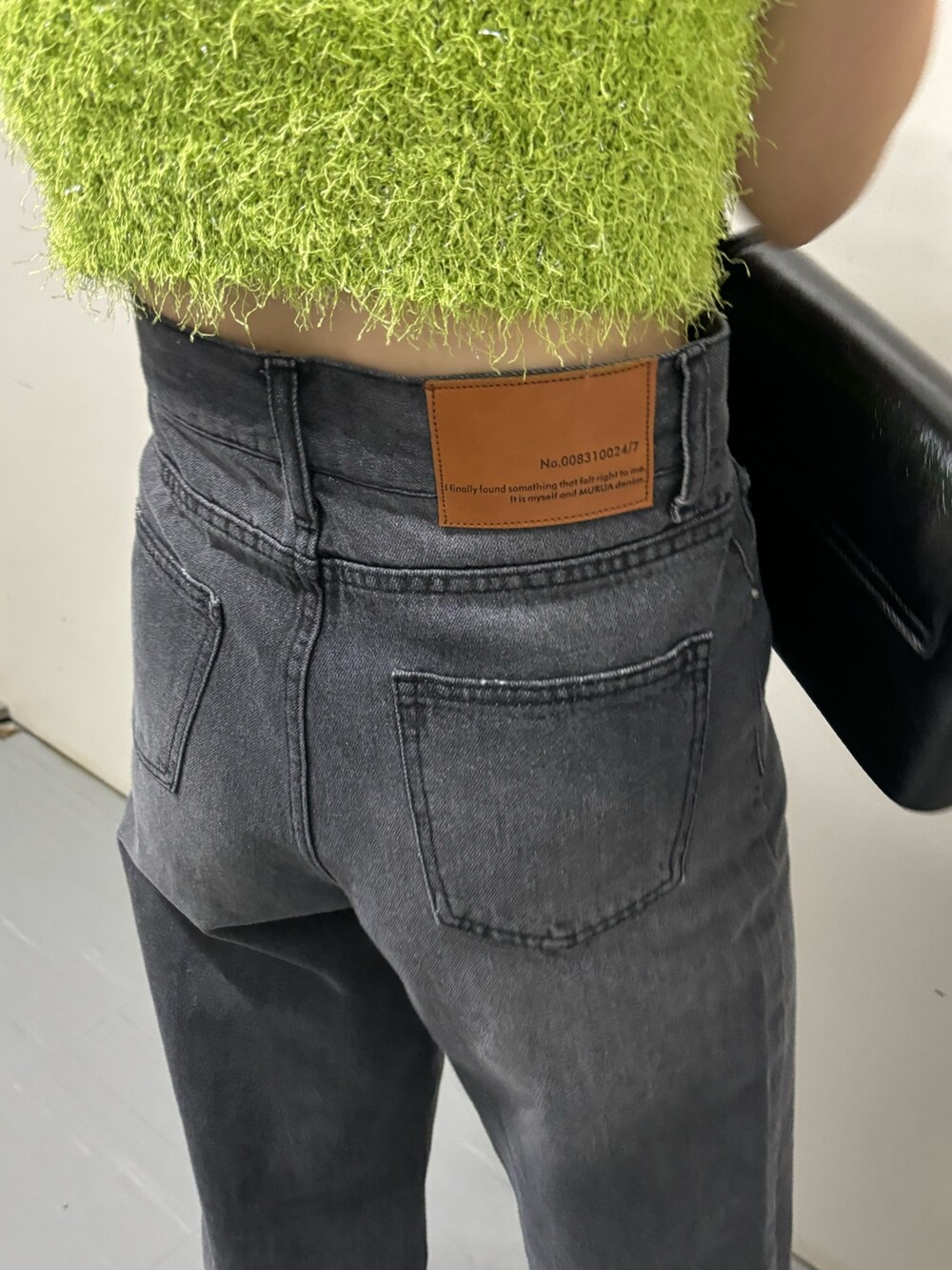 ブラック系のショルダーバッグ、グリーン系のニット/セーター、ブラック系のデニムパンツを着用したレディースの春コーディネートの9枚目の写真