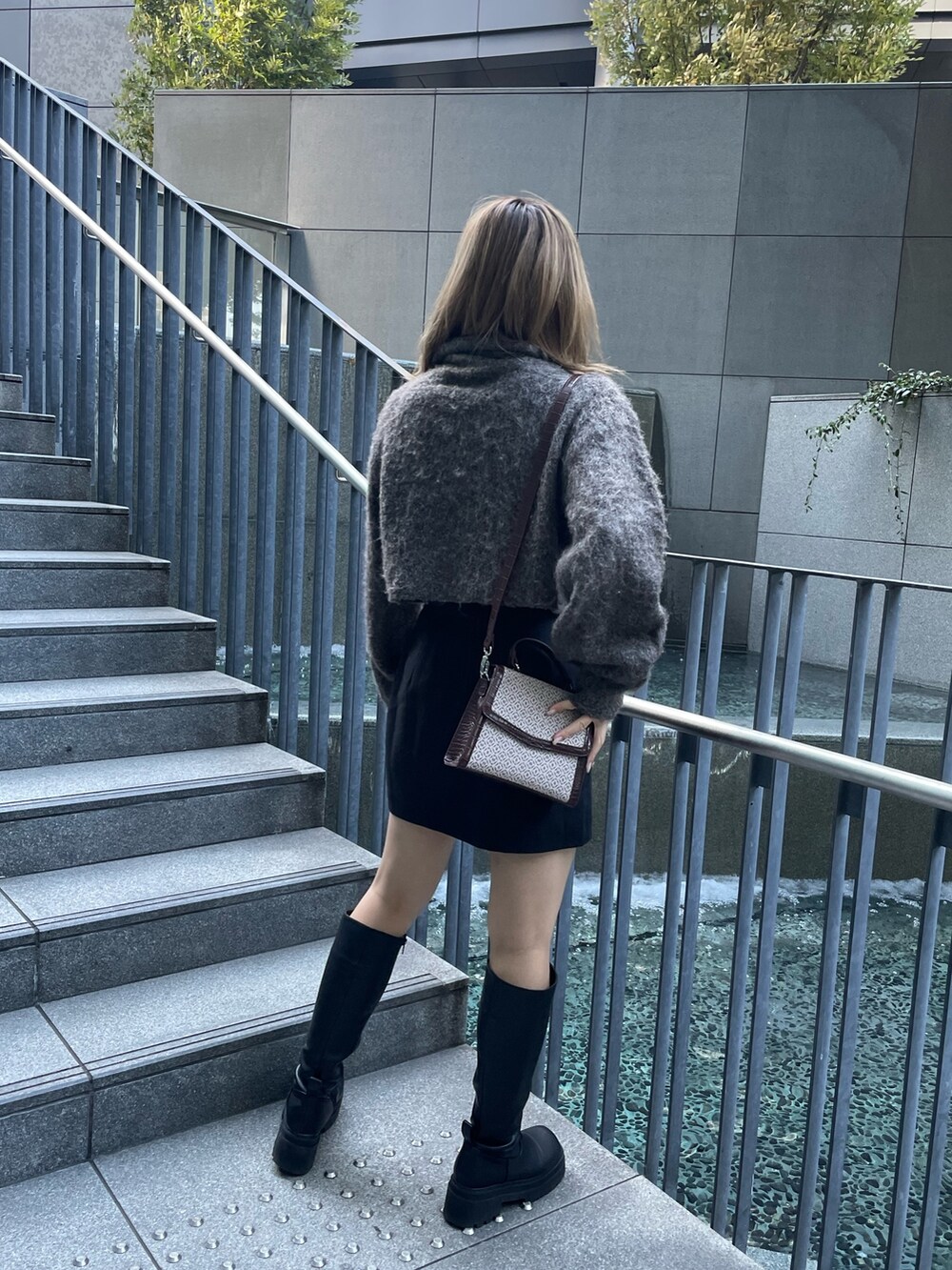 ブラウン系のニット/セーター、ブラック系のスカート、その他のハンドバッグを着用したレディースの秋コーディネートの5枚目の写真