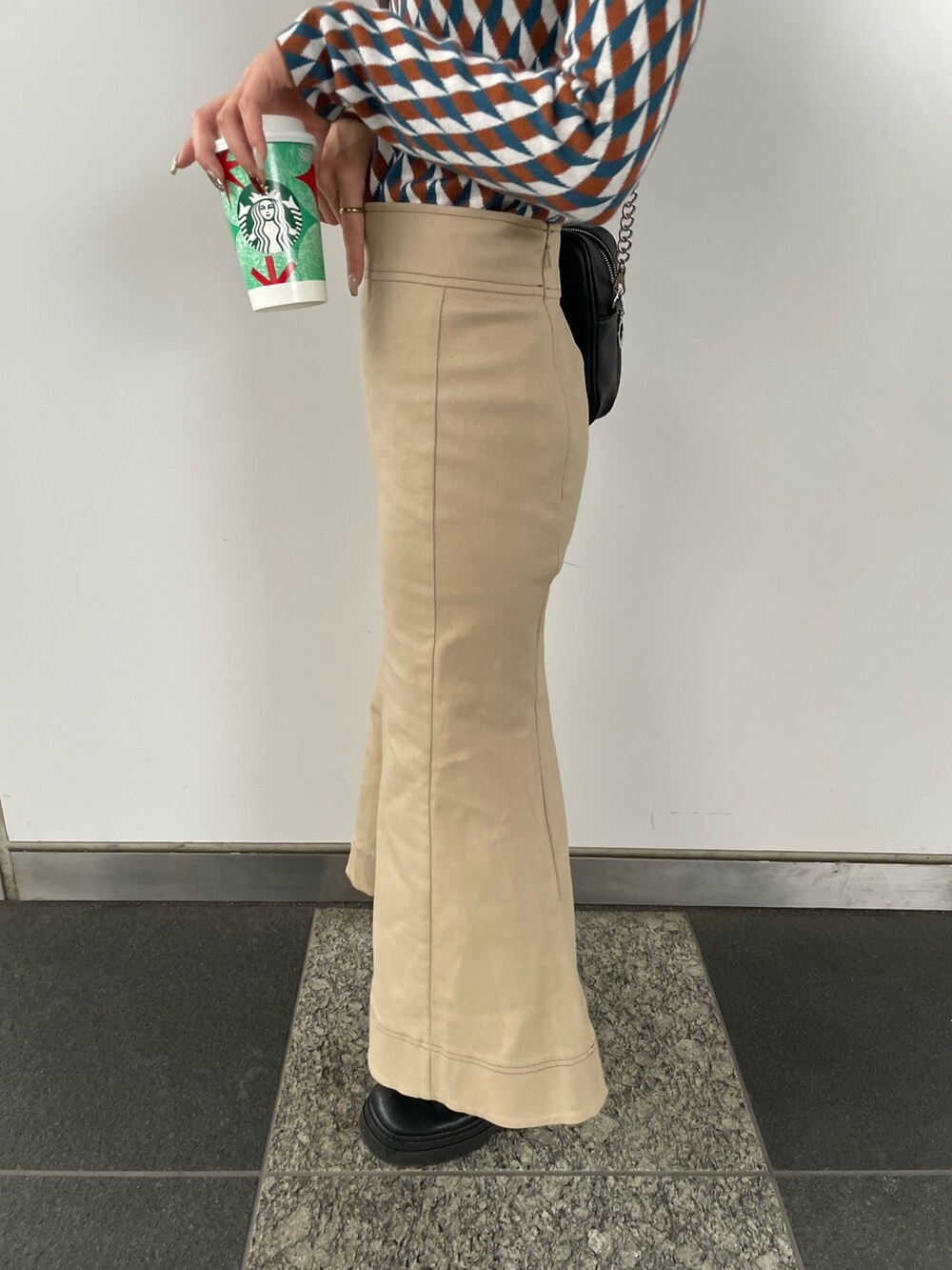 ブラック系のショルダーバッグ、オレンジ系のニット/セーター、ベージュ系のスカートを着用したレディースの秋コーディネートの9枚目の写真