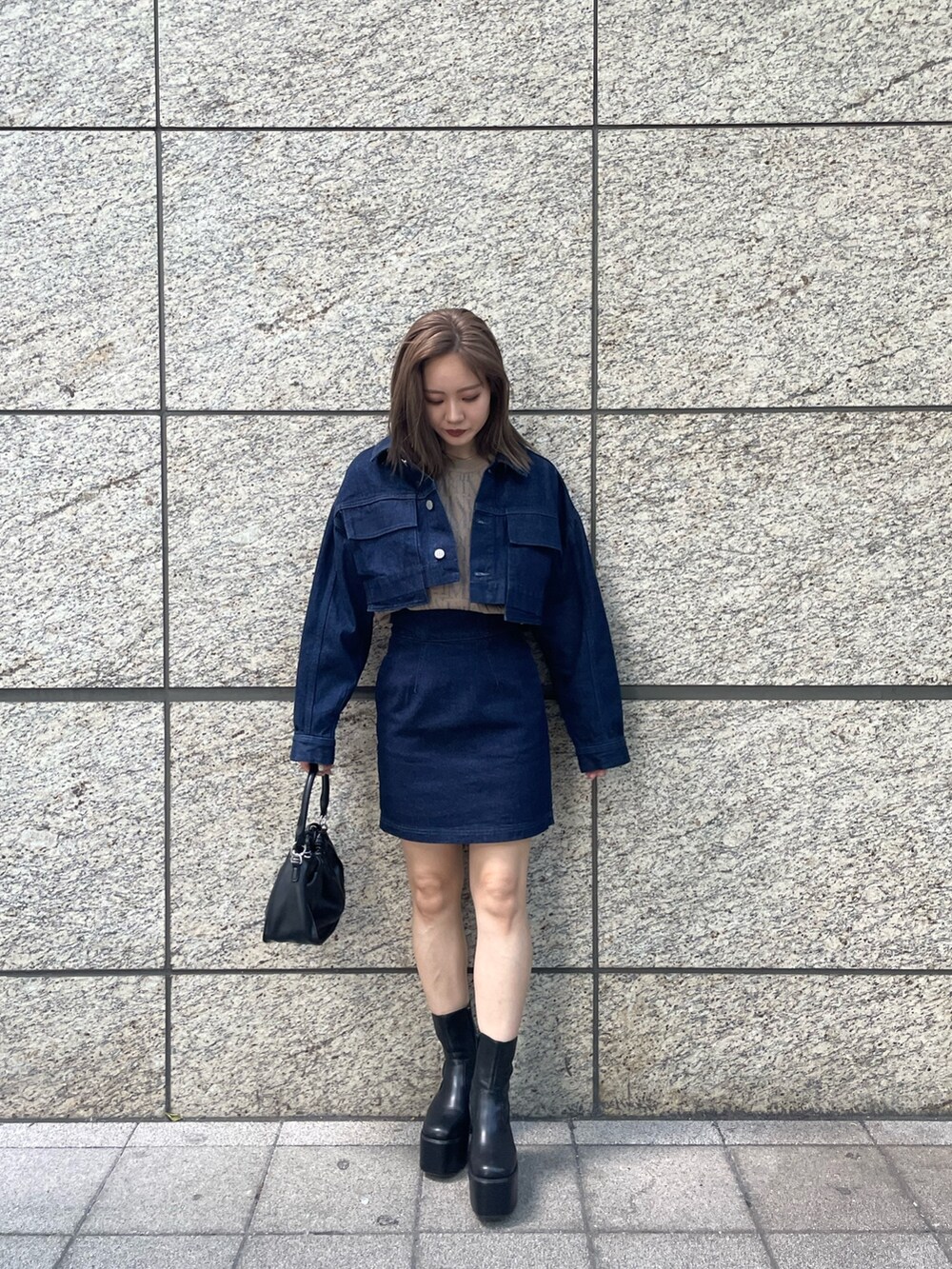 ベージュ系のニット/セーター、ブルー系のスカート、ブラック系のブーツを着用したレディースの夏コーディネートの3枚目の写真