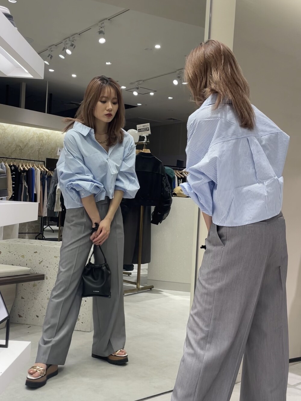 ブルー系のシャツ/ブラウス、グレー系のスラックス、その他のサンダルを着用したレディースの春コーディネートの4枚目の写真