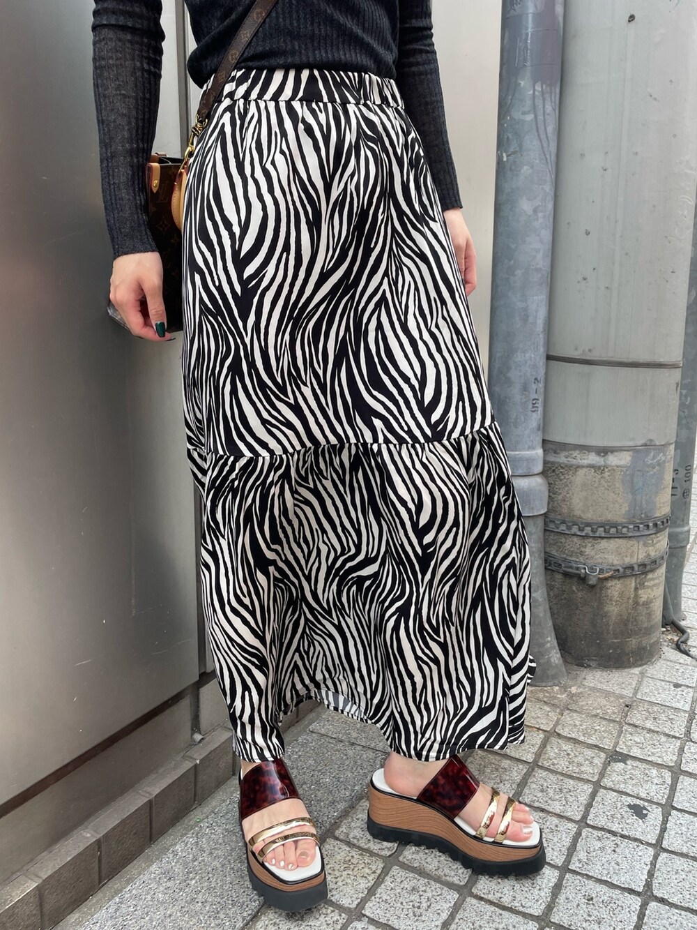 ブラック系のニット/セーター、ホワイト系のスカート、その他のサンダルを着用したレディースの春コーディネートの7枚目の写真