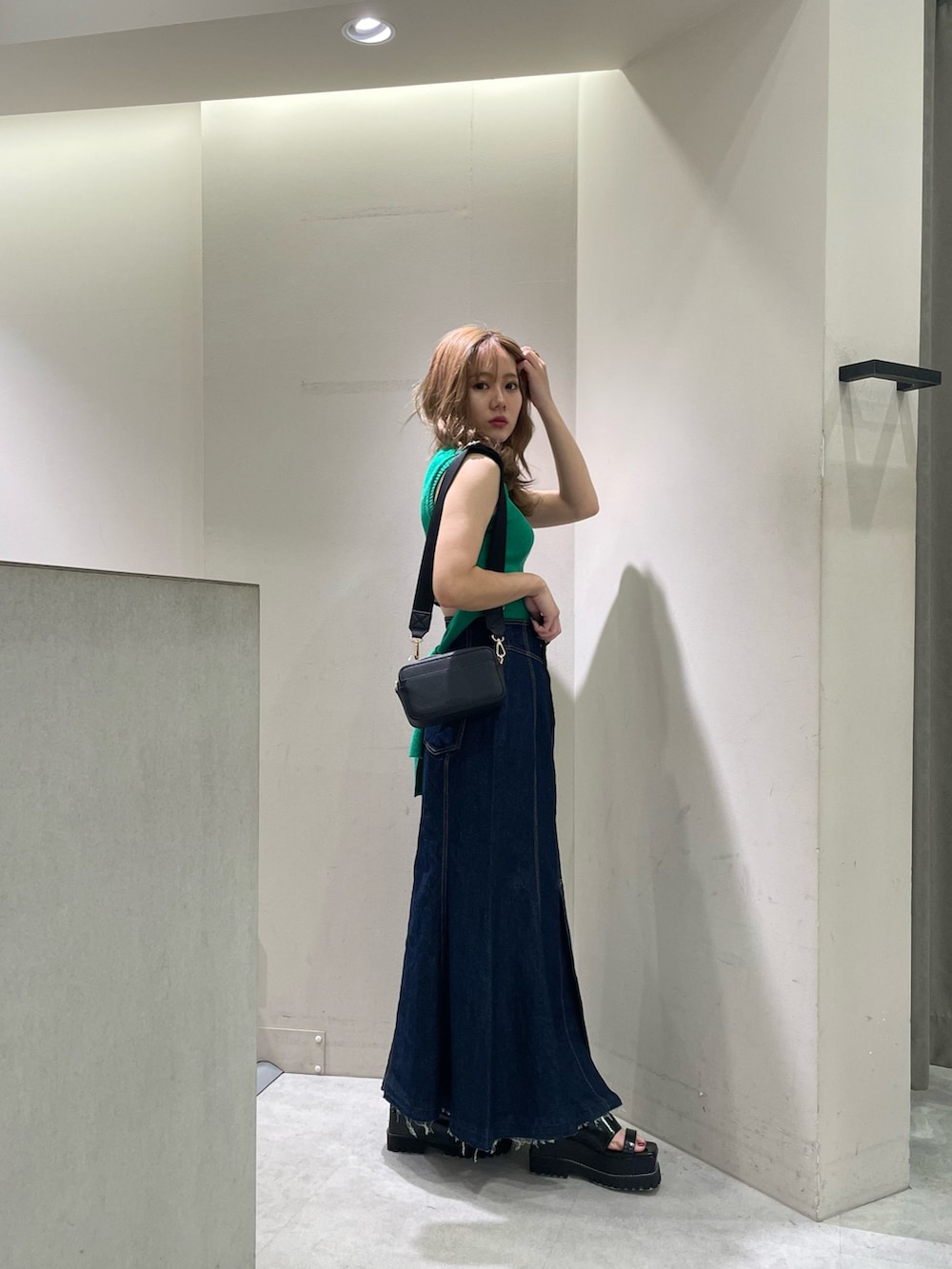 ブラック系のサンダル、ブラック系のショルダーバッグ、グリーン系のタンクトップを着用したレディースの夏コーディネートの2枚目の写真