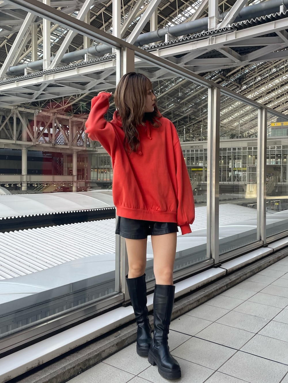 オレンジ系のパーカー、ブラック系のブーツを着用したレディースの秋コーディネートの4枚目の写真