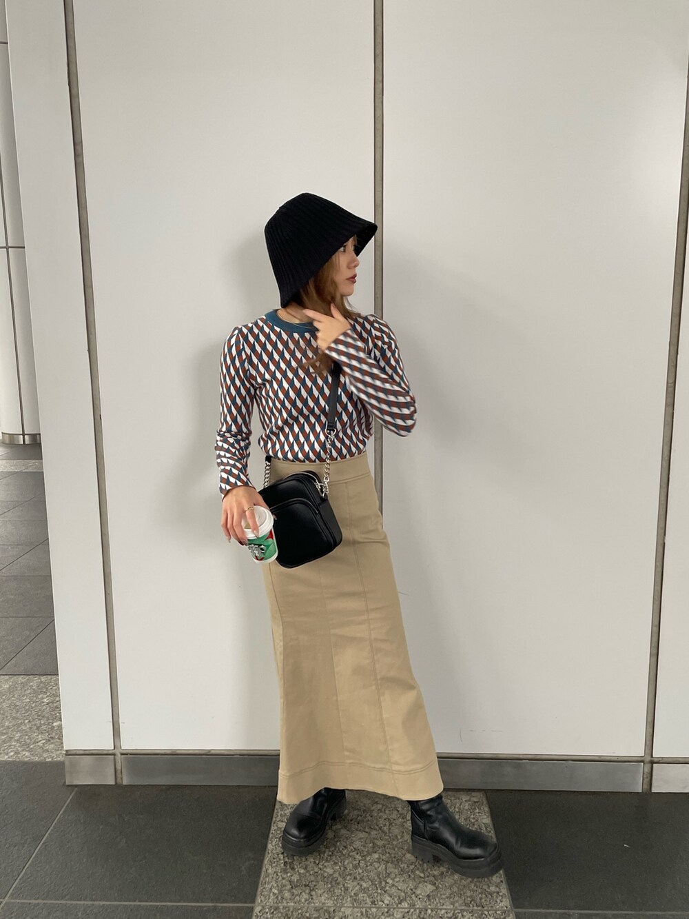 ブラック系のショルダーバッグ、オレンジ系のニット/セーター、ベージュ系のスカートを着用したレディースの秋コーディネートの4枚目の写真