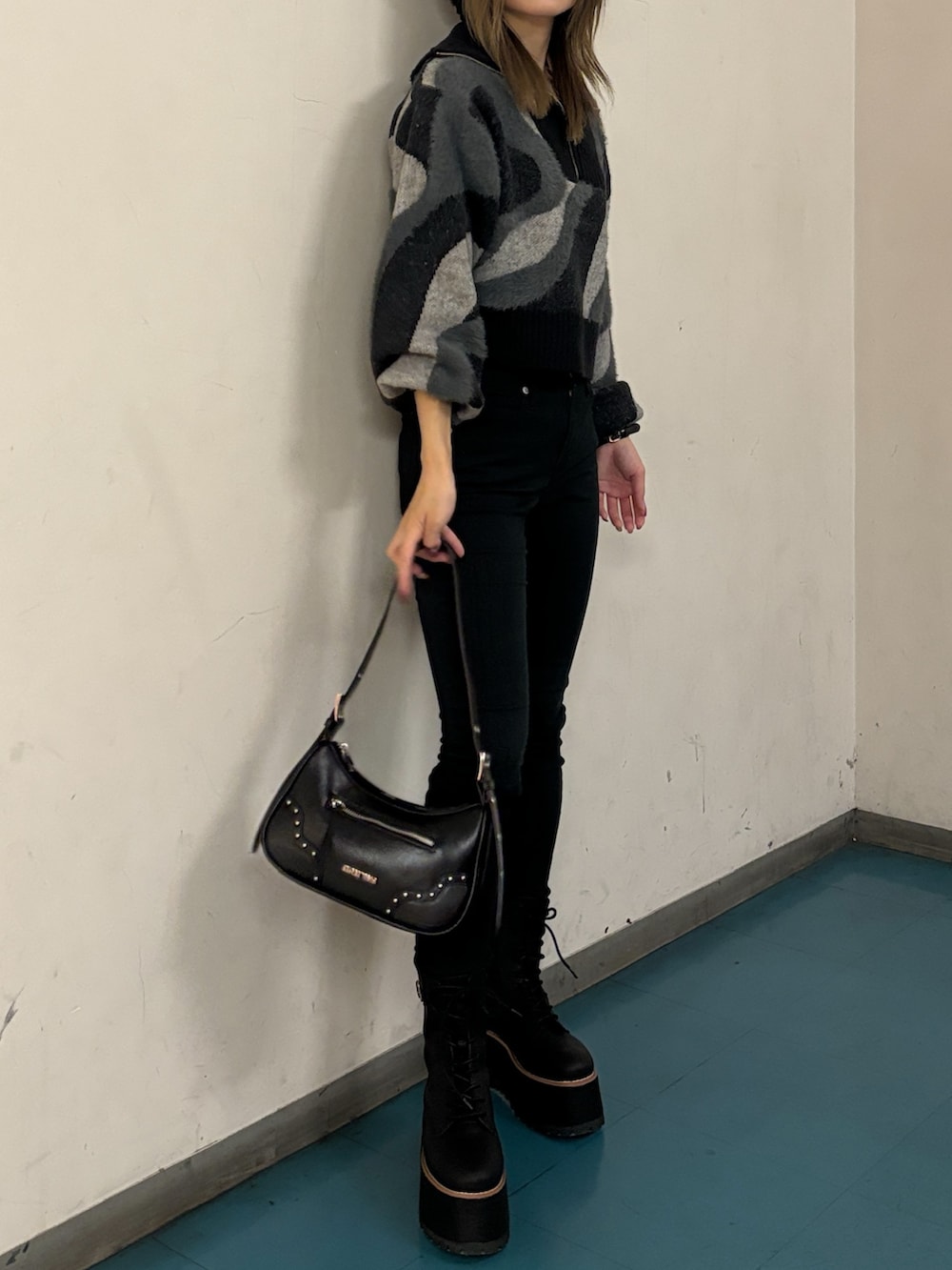 ブラック系のニット/セーター、ブラック系のハンドバッグ、ブラック系のブーツを着用したレディースの秋コーディネートの2枚目の写真