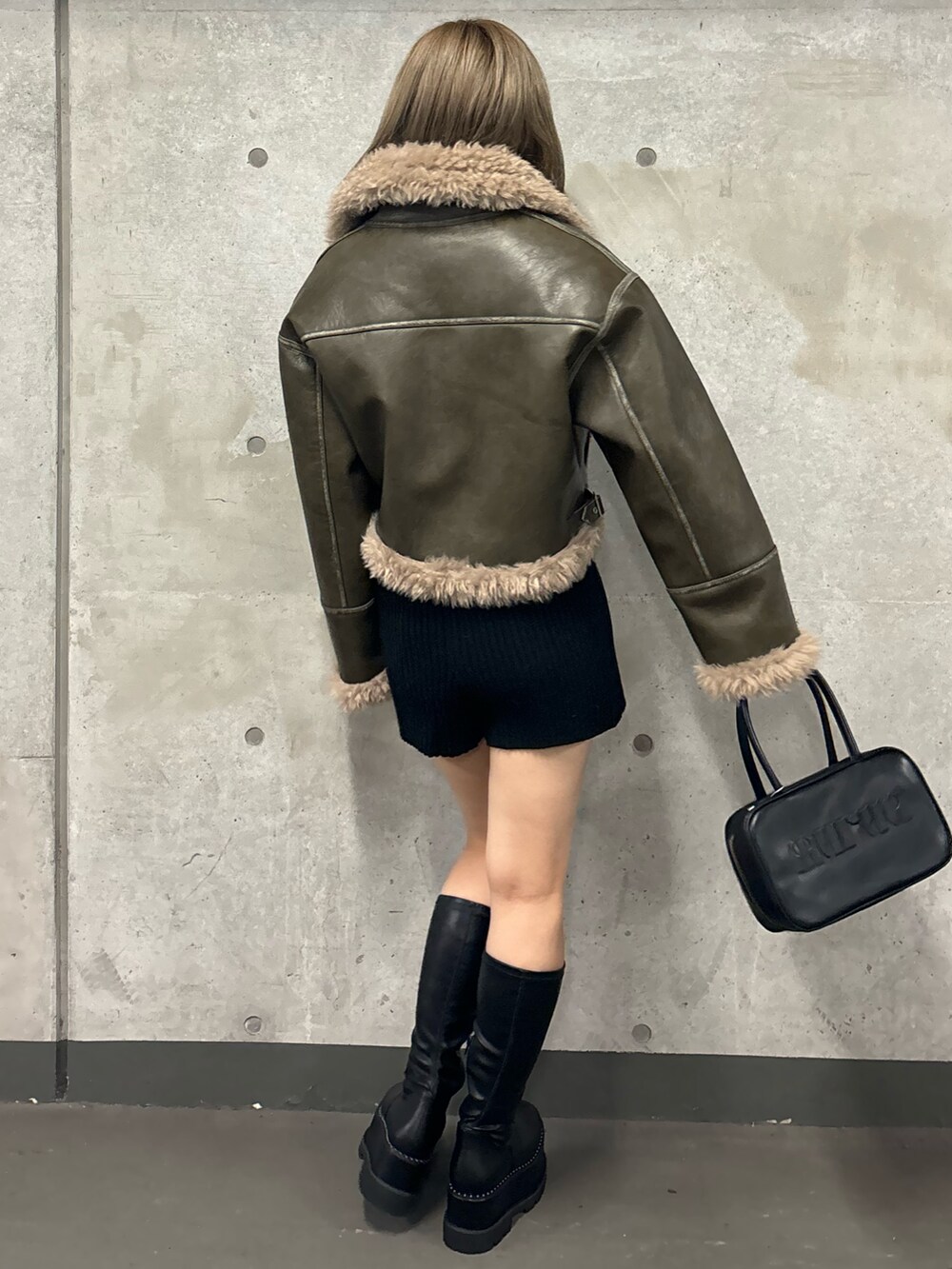 ブラック系のその他パンツ、ブラック系のブーツ、グリーン系のムートンコートを着用したレディースの夏コーディネートの5枚目の写真