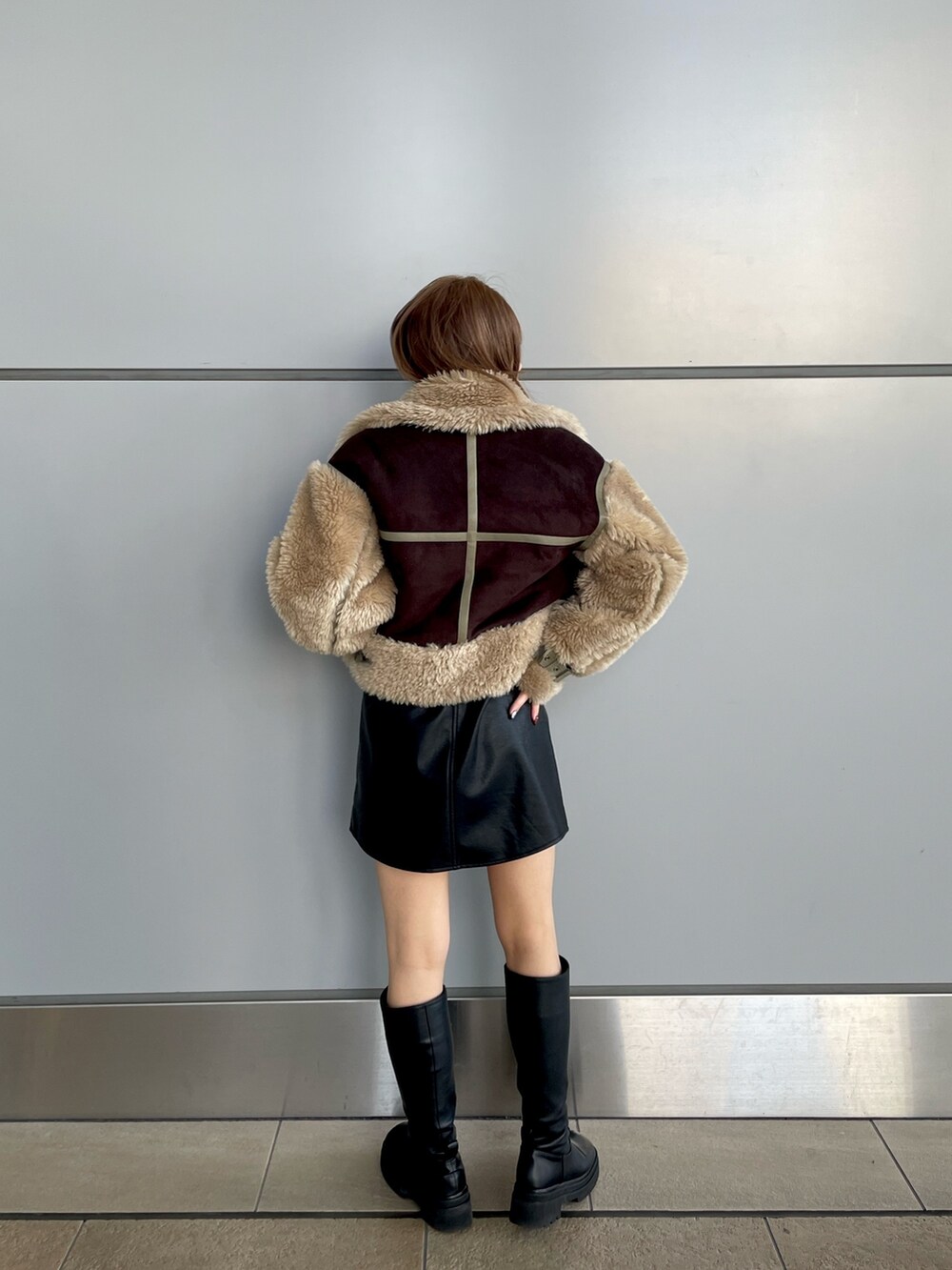 ブラック系のワンピース、ホワイト系のニット/セーター、ブラウン系のムートンコートを着用したレディースの冬コーディネートの2枚目の写真