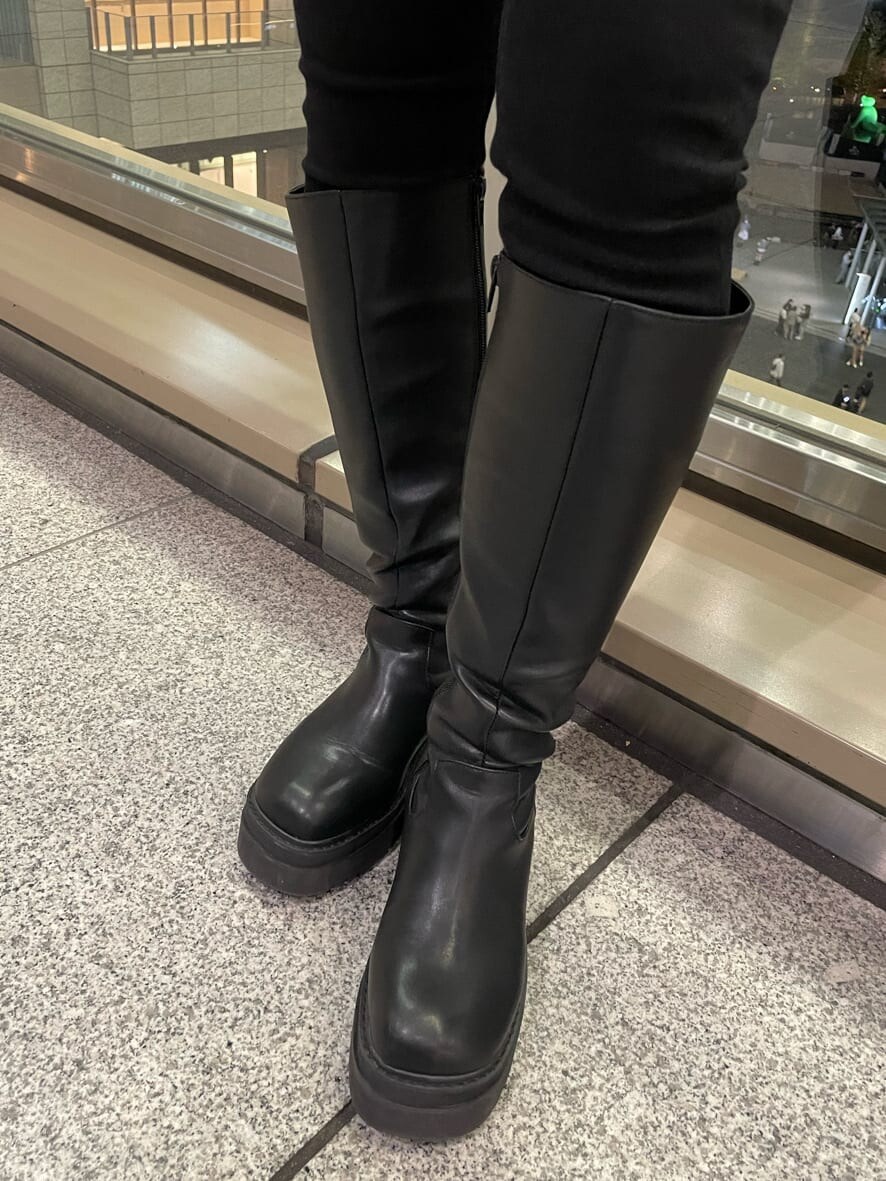 ブラック系のダウンベスト、ブラック系のブーツ、パープル系のニット/セーターを着用したレディースの秋コーディネートの6枚目の写真