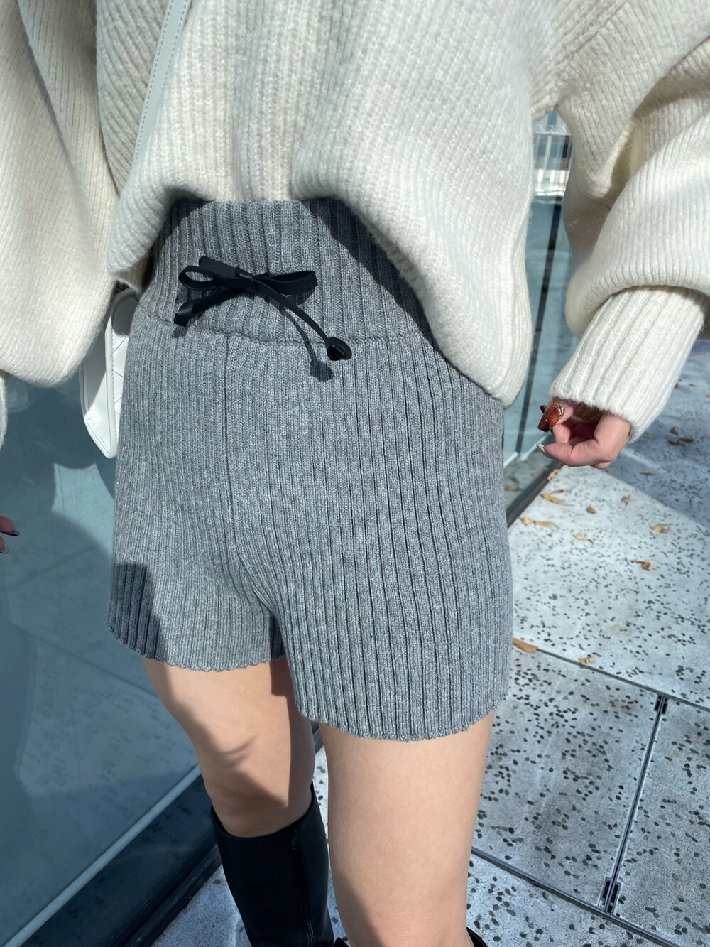 ホワイト系のニット/セーター、グレー系のスウェットパンツ、ブラック系のブーツを着用したレディースの秋コーディネートの7枚目の写真