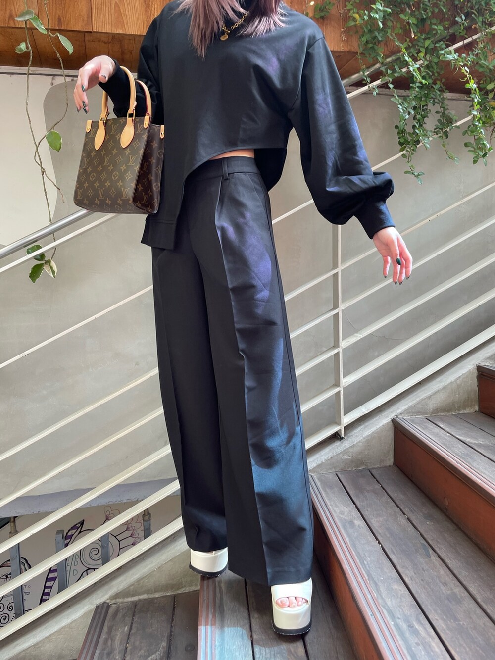 ブラック系のTシャツ/カットソー、ブラック系のスラックス、ホワイト系のサンダルを着用したレディースの春コーディネートの7枚目の写真