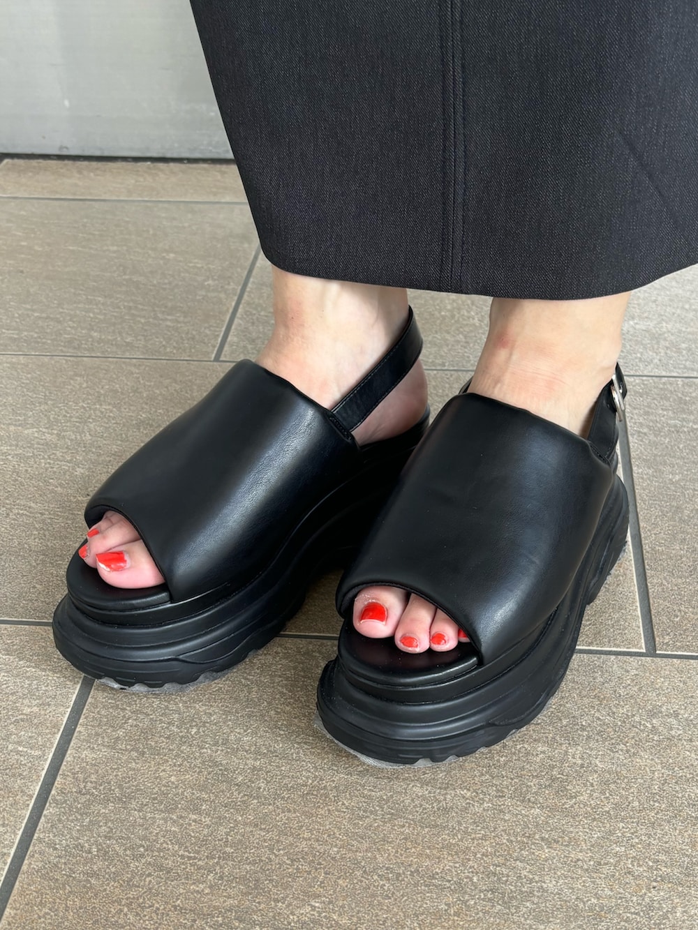 グレー系のニット/セーター、シルバー系のハンドバッグ、ブラック系のスカートを着用したレディースの夏コーディネートの9枚目の写真