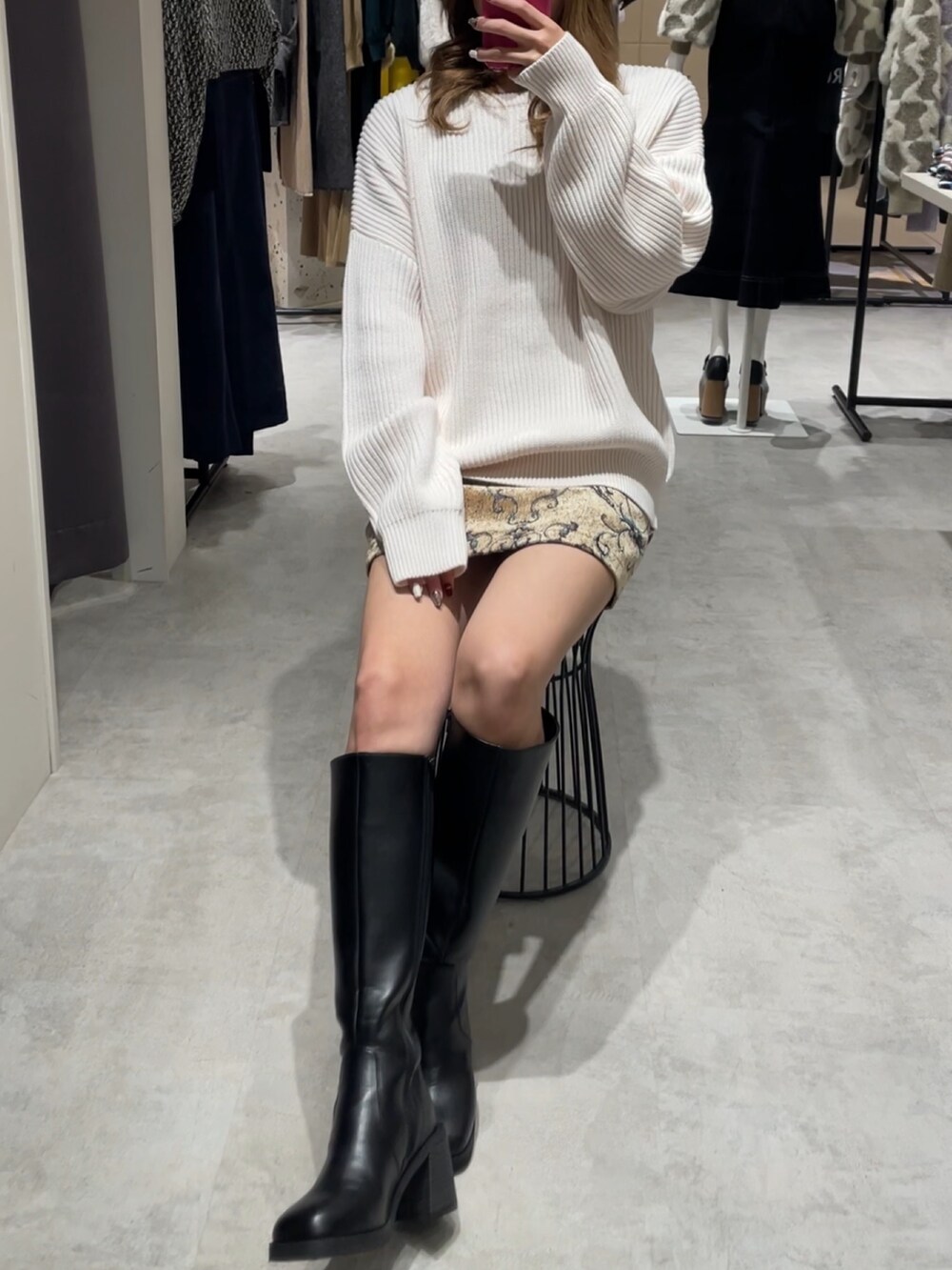 ブラウン系のスカート、ブラック系のブーツ、ホワイト系のニット/セーターを着用したレディースの冬コーディネートの2枚目の写真