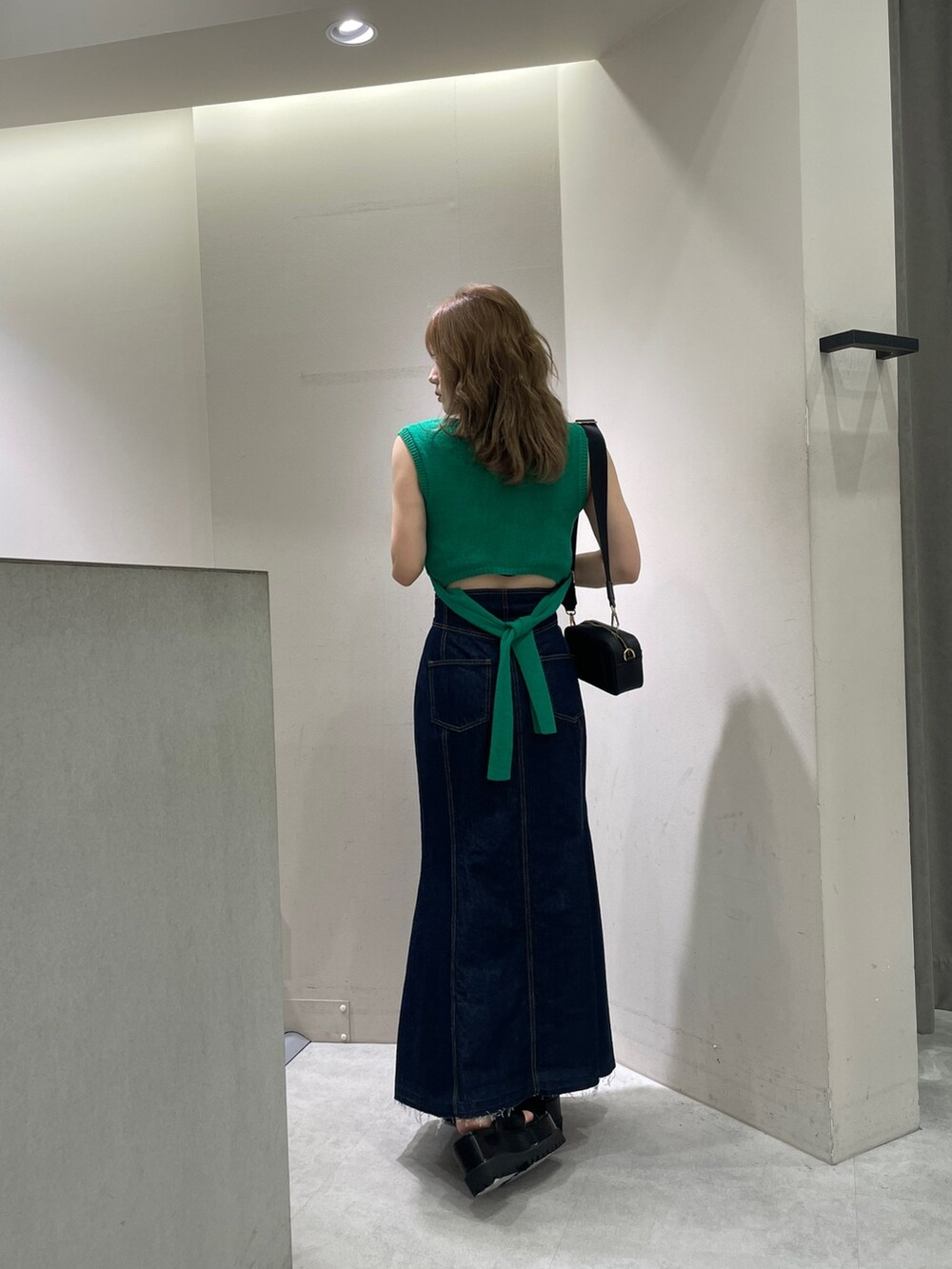 ブラック系のサンダル、ブラック系のショルダーバッグ、グリーン系のタンクトップを着用したレディースの夏コーディネートの4枚目の写真