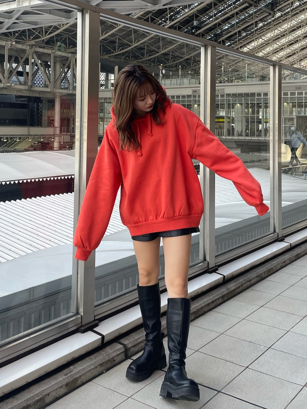 オレンジ系のパーカー、ブラック系のブーツを着用したレディースの秋コーディネートの2枚目の写真