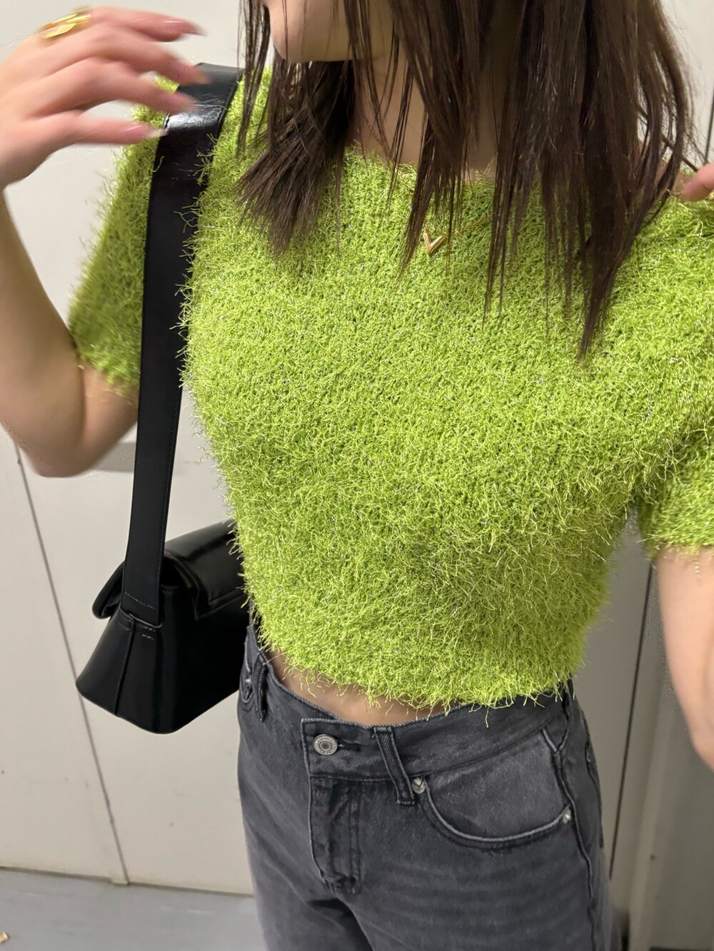 ブラック系のショルダーバッグ、グリーン系のニット/セーター、ブラック系のデニムパンツを着用したレディースの春コーディネートの7枚目の写真