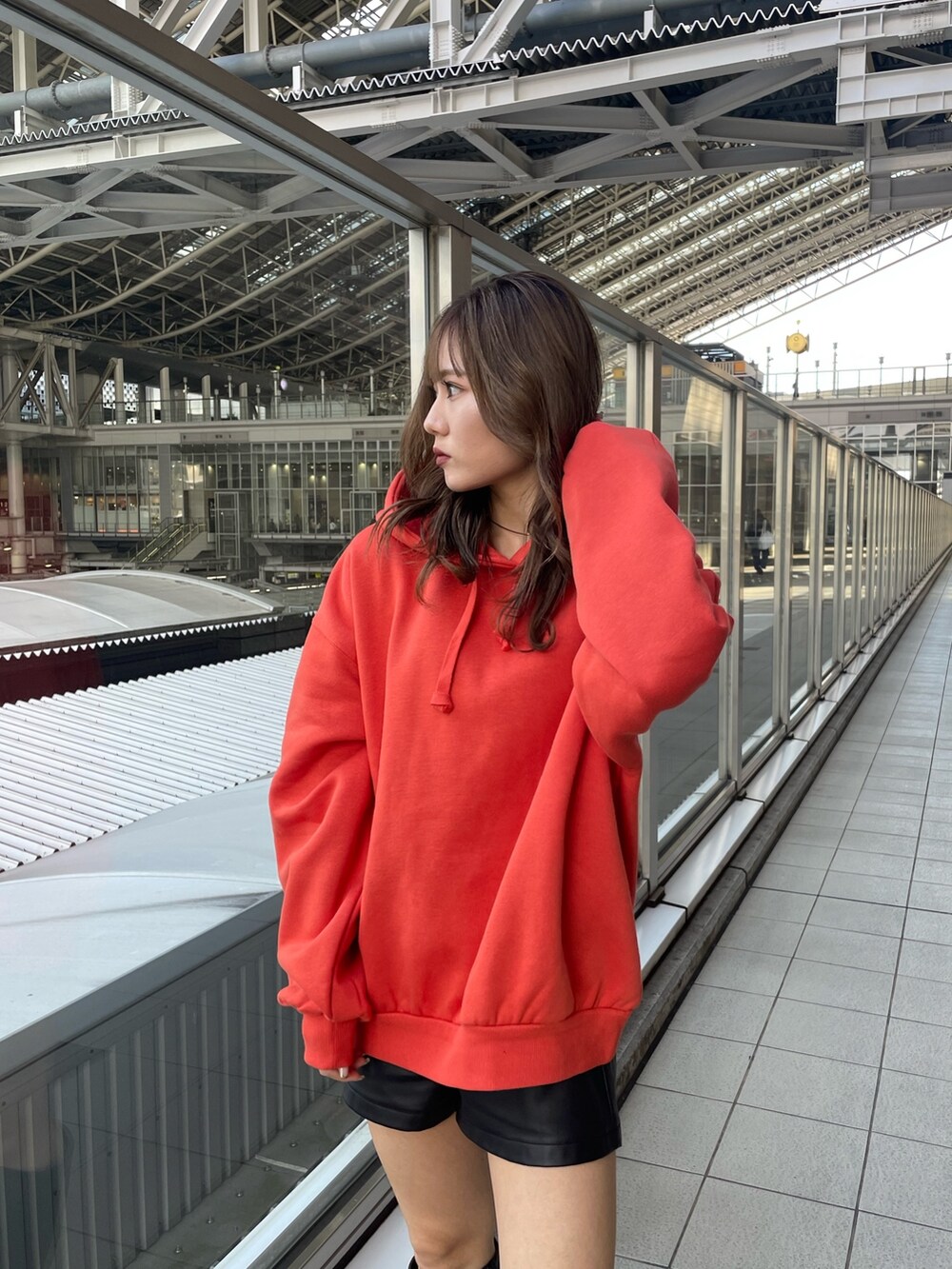 オレンジ系のパーカー、ブラック系のブーツを着用したレディースの秋コーディネートの5枚目の写真