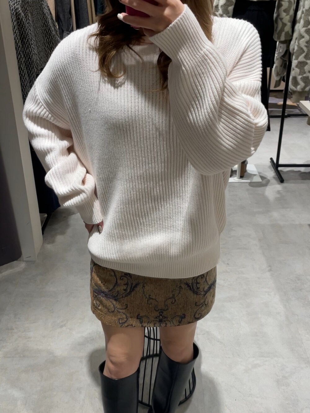 ブラウン系のスカート、ブラック系のブーツ、ホワイト系のニット/セーターを着用したレディースの冬コーディネートの4枚目の写真