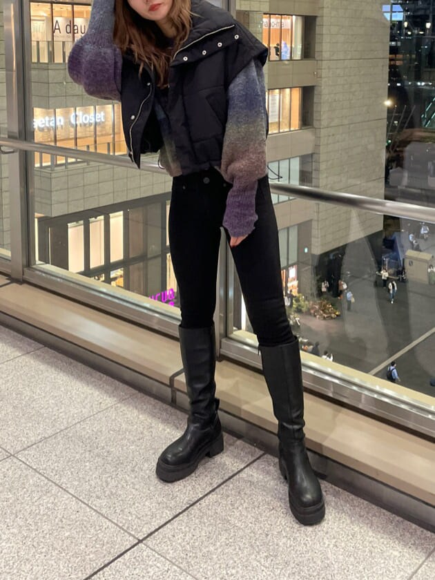 ブラック系のダウンベスト、ブラック系のブーツ、パープル系のニット/セーターを着用したレディースの秋コーディネートの7枚目の写真