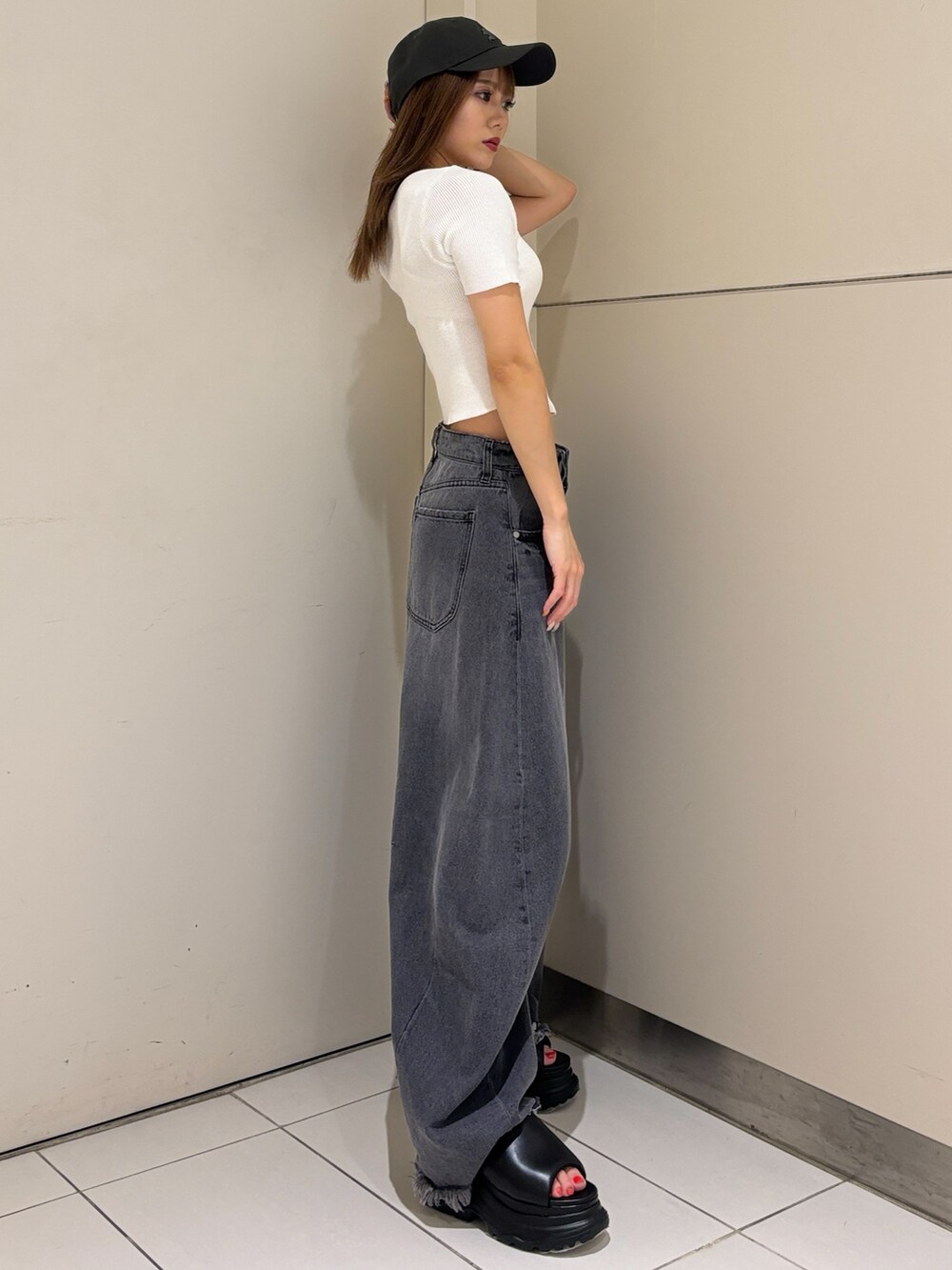ブラック系のサンダル、ブラック系のデニムパンツ、ホワイト系のニット/セーターを着用したレディースの夏コーディネートの4枚目の写真