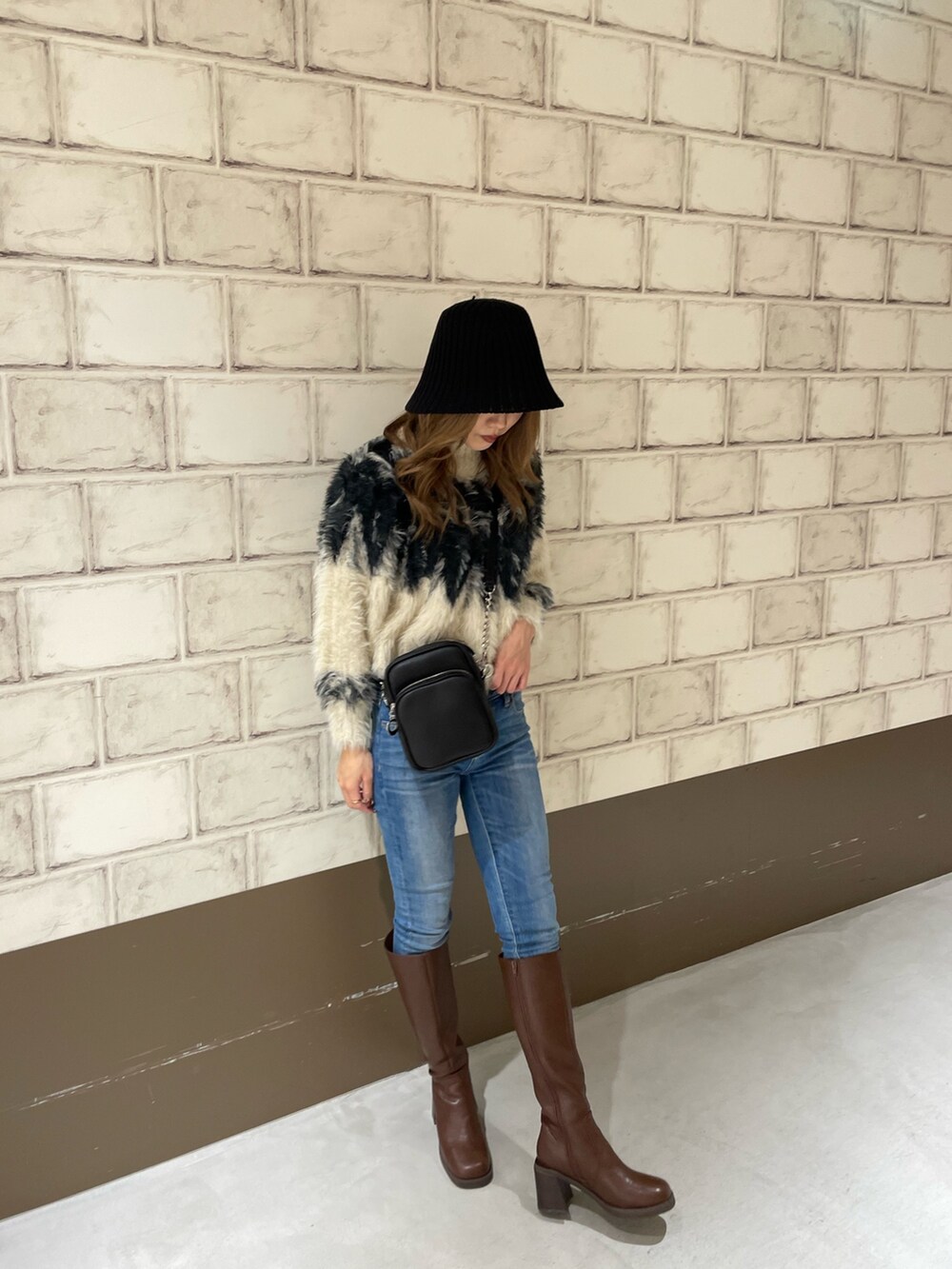 ホワイト系のニット/セーター、ブラウン系のブーツ、ブラック系のハットを着用したレディースの秋コーディネートの4枚目の写真