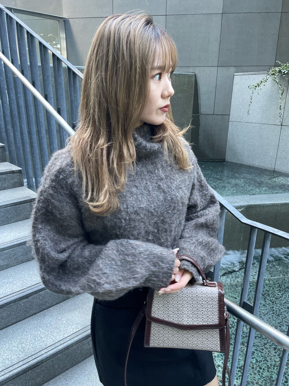 ブラウン系のニット/セーター、ブラック系のスカート、その他のハンドバッグを着用したレディースの秋コーディネートの4枚目の写真