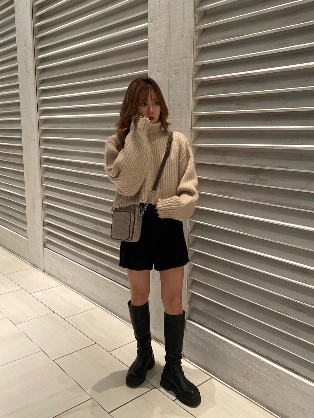 ホワイト系のニット/セーター、ブラック系のブーツ、その他のショルダーバッグを着用したレディースの秋コーディネートの2枚目の写真