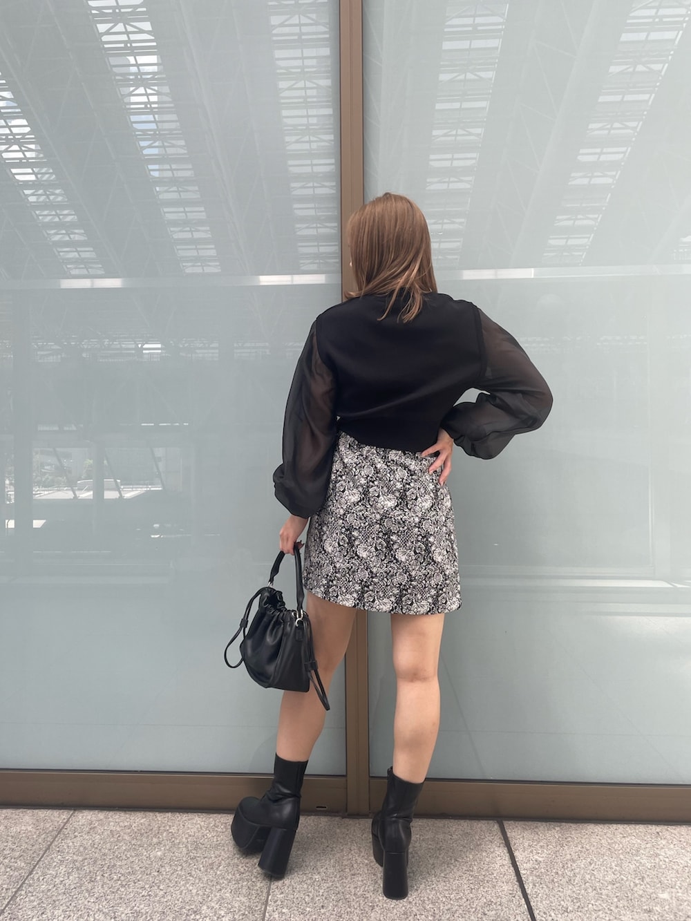 ブラック系のニット/セーター、ブラック系のブーツ、ブラック系のスカートを着用したレディースの夏コーディネートの4枚目の写真