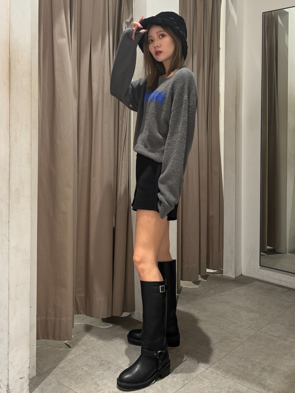 グレー系のニット/セーター、ブラック系のその他パンツ、ブラック系のブーツを着用したレディースの秋コーディネートの2枚目の写真