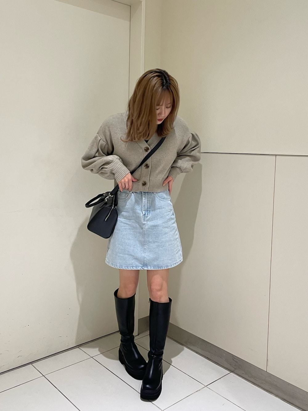 ホワイト系のカーディガン/ボレロ、ブラック系のブーツ、ブラック系のハンドバッグを着用したレディースの春コーディネートの2枚目の写真